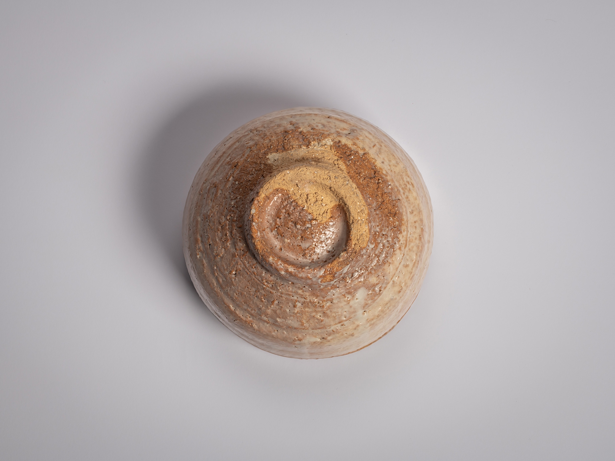 Foot view of a Hagi chawan by Miwa X, showing a raised circular kōdai with a recessed center, partially...
