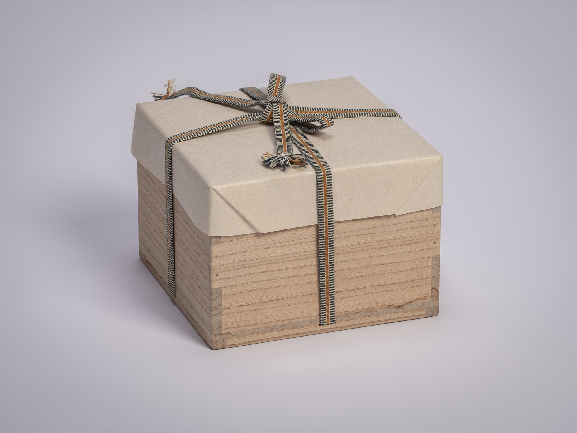 Wooden tomobako storage box for an Ido chawan by Tsujimura, wrapped in protective paper and secured...