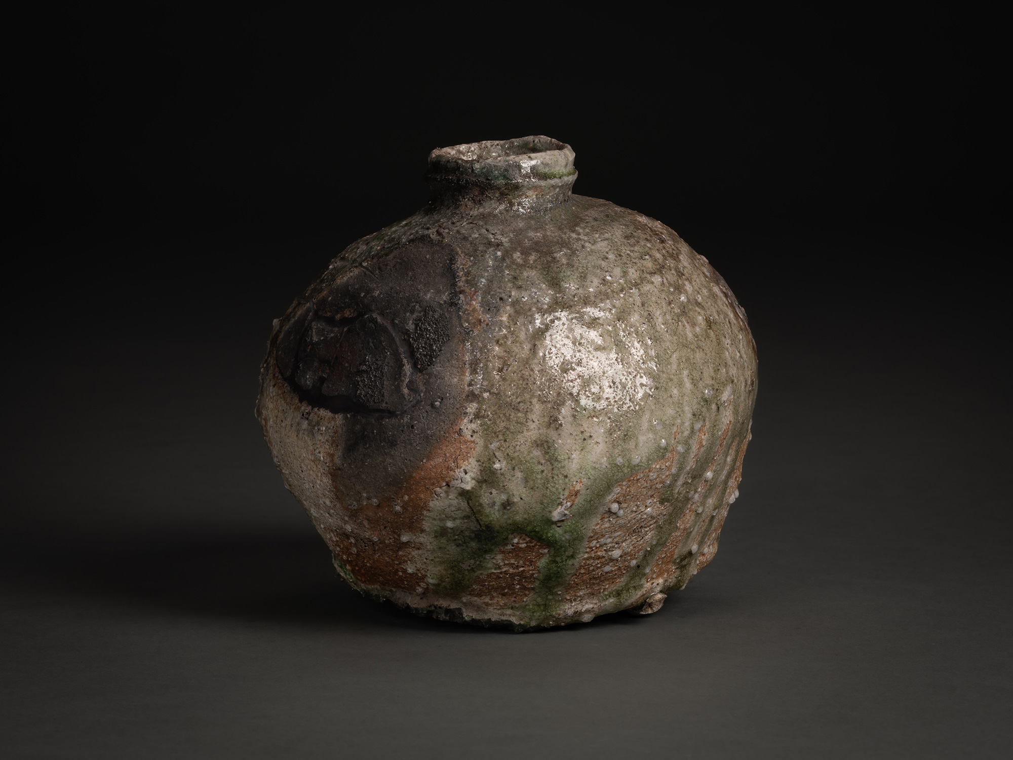 Side view of Iga Broken Jar by Shiro Tsujimura, a rounded ceramic vessel with a narrow neck and...