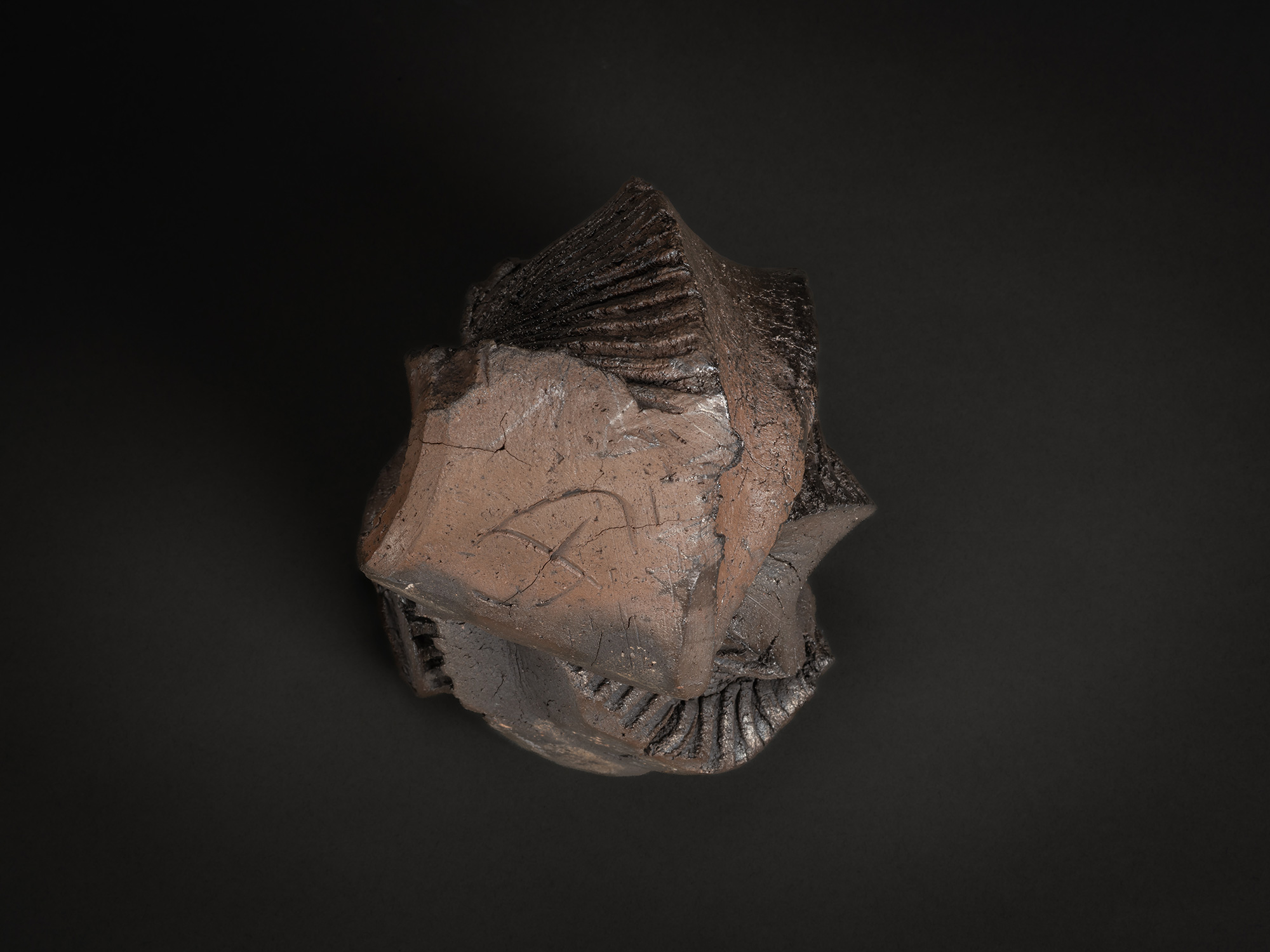 A view of the base and underside of a dark stoneware sculpture by Shozo Michikawa. The foot is...