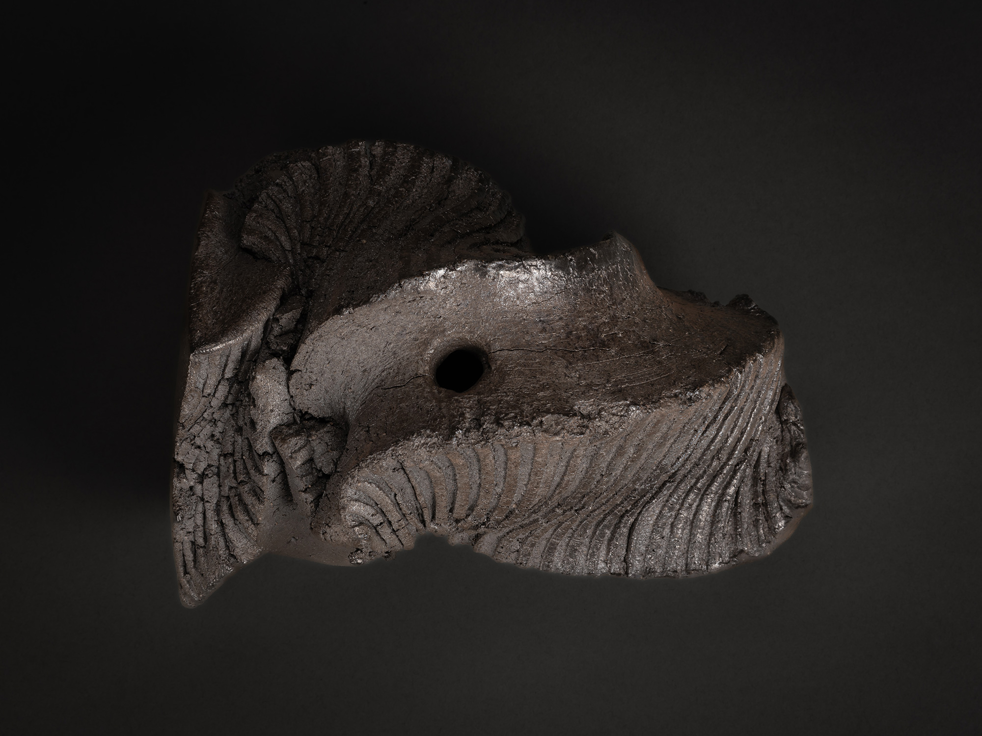 An overhead aerial view of a dark stoneware sculptural form by Shozo Michikawa. The perspective...