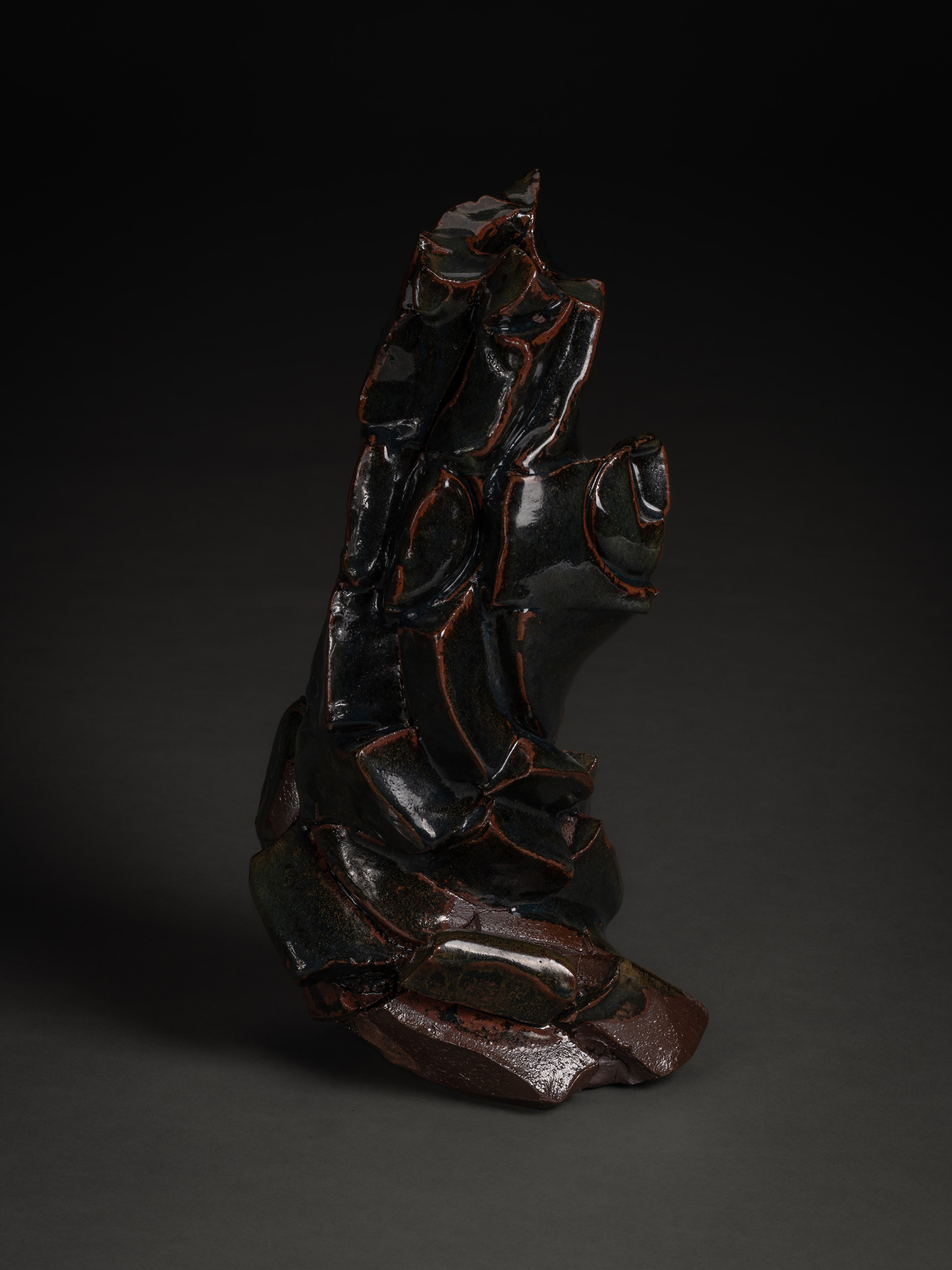 A dark, twisted stoneware sculpture by Shozo Michikawa featuring deep horizontal ridges and a square...