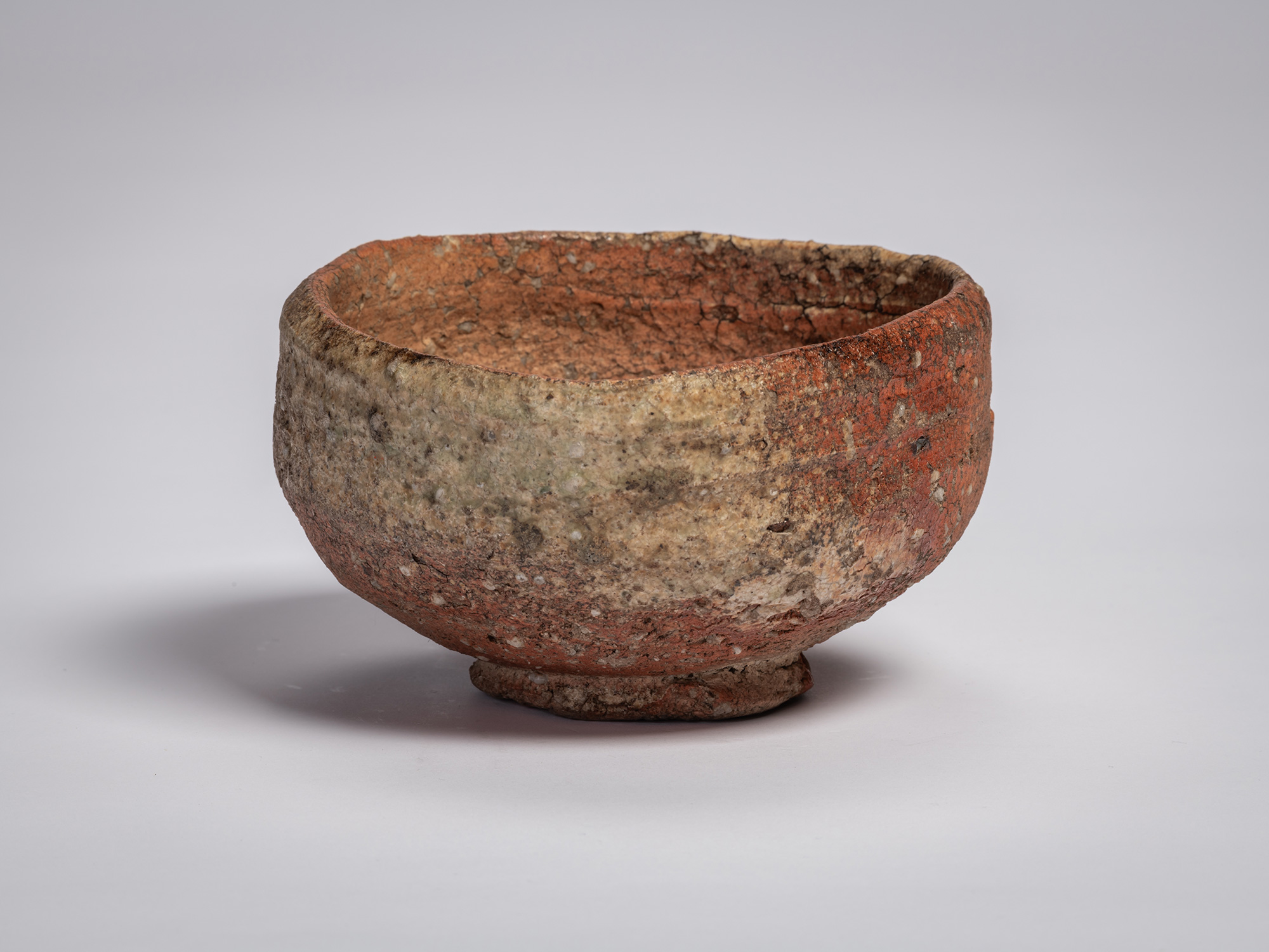 Shigaraki chawan tea bowl by Tsujimura, with a low, rounded form, rough granular clay body, and...