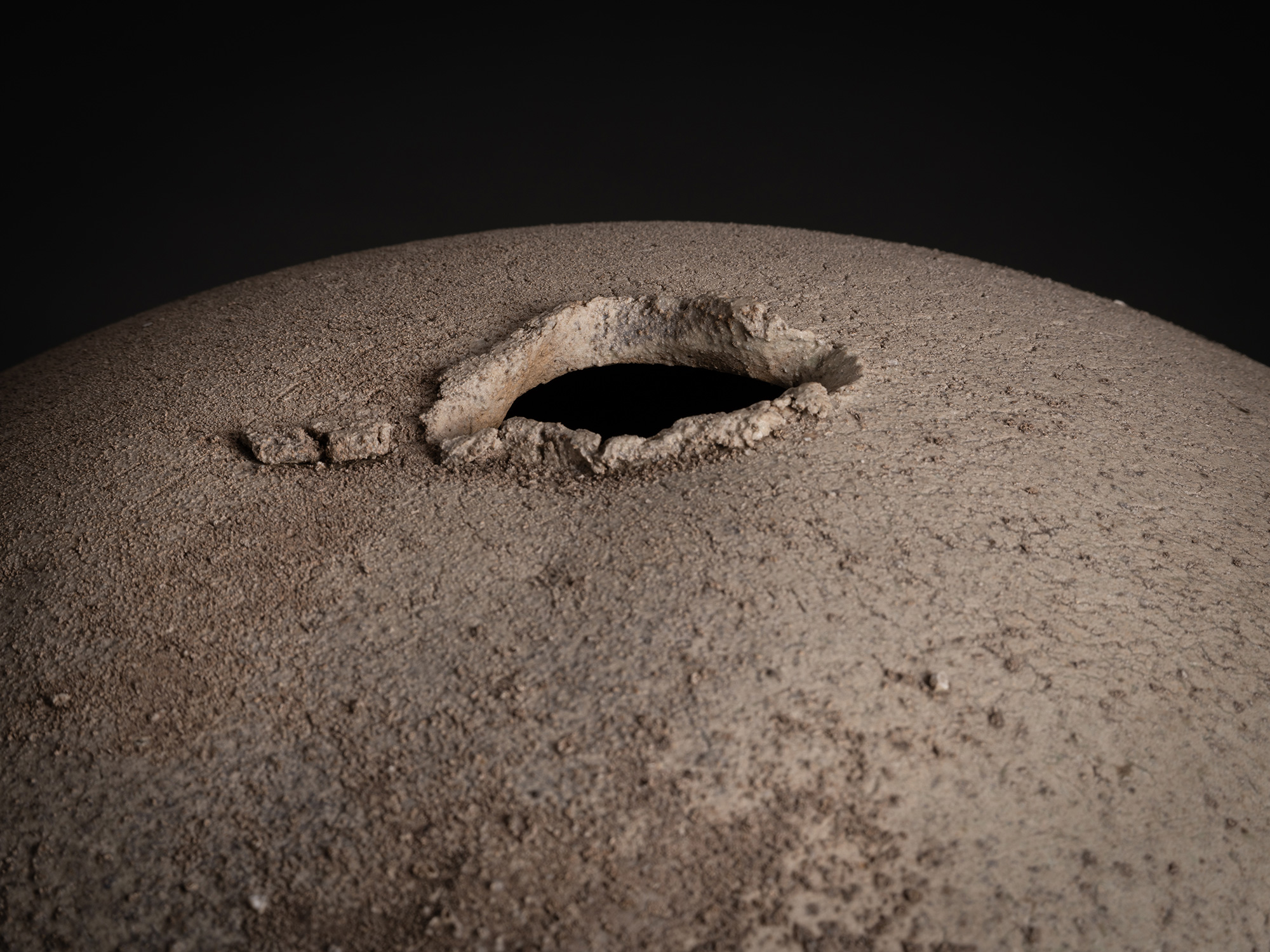 Detail of Sphere by Tsujimura showing the top opening: a small, irregularly shaped aperture with...