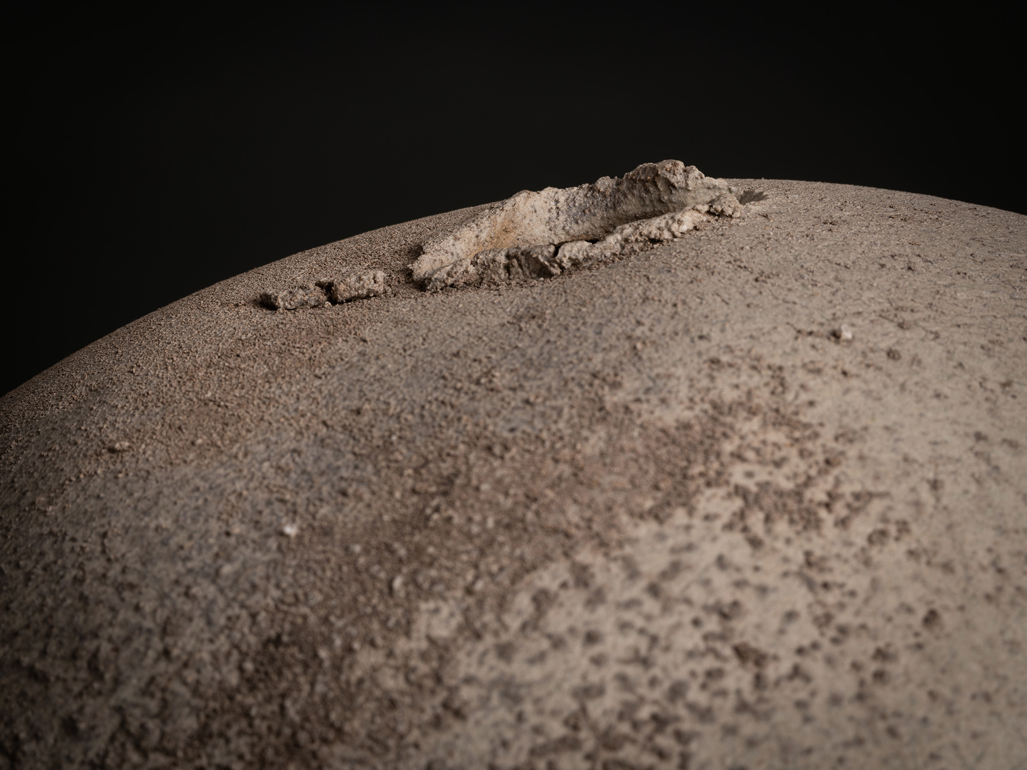 Detail of Sphere by Tsujimura showing the top opening from a low angle: a shallow, irregular aperture...