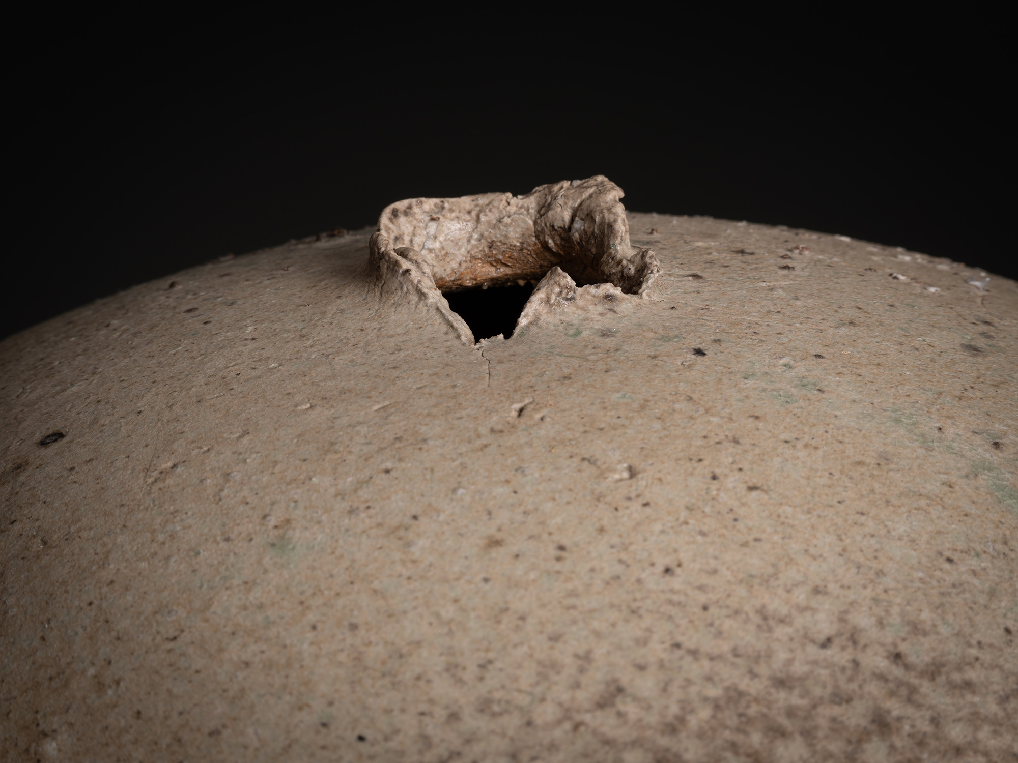 Detail of Sphere by Tsujimura showing the top opening: a small, irregular aperture with a thick,...
