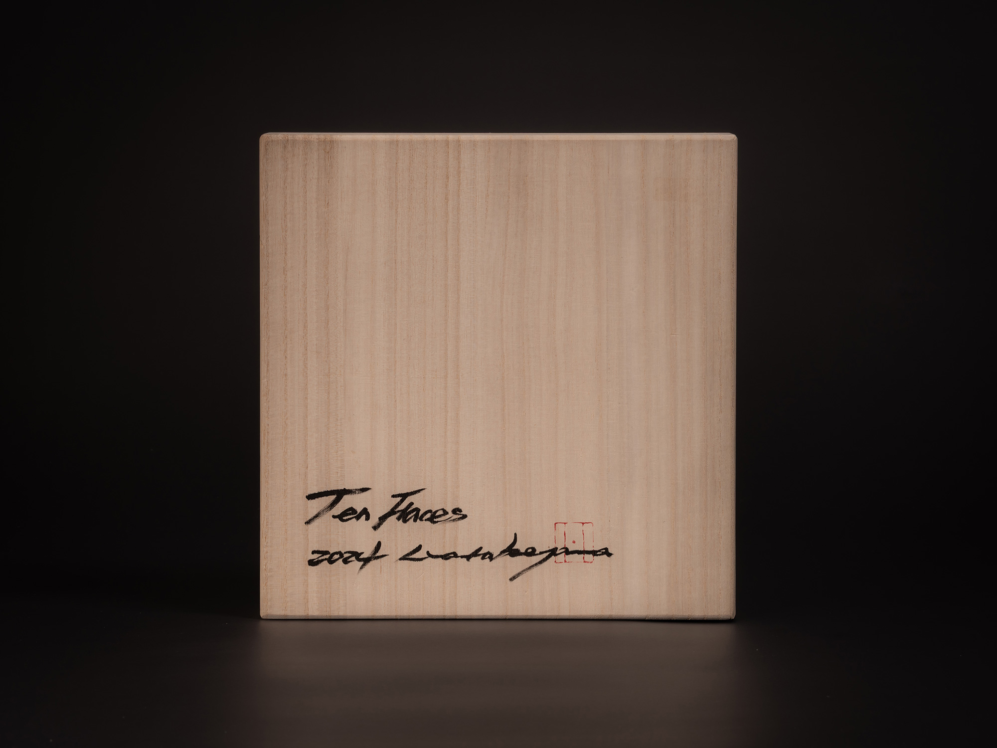Wooden tomobako storage box for Ten Faces II by Koji Hatakeyama, showing a light wood grain surface...