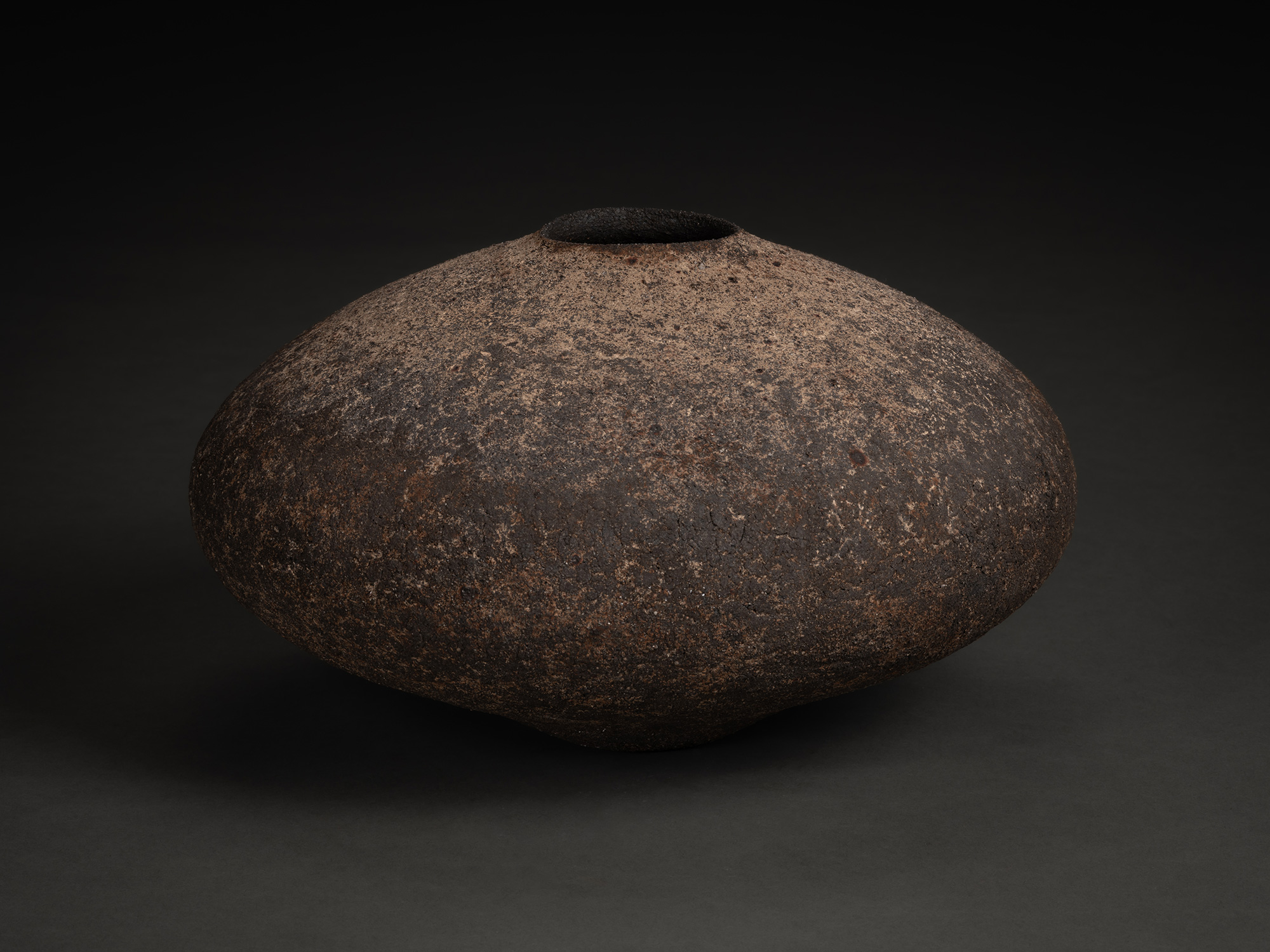 Vase by Jun Aoki, a low, wide ceramic vessel with a flattened, rounded form and narrow opening,...
