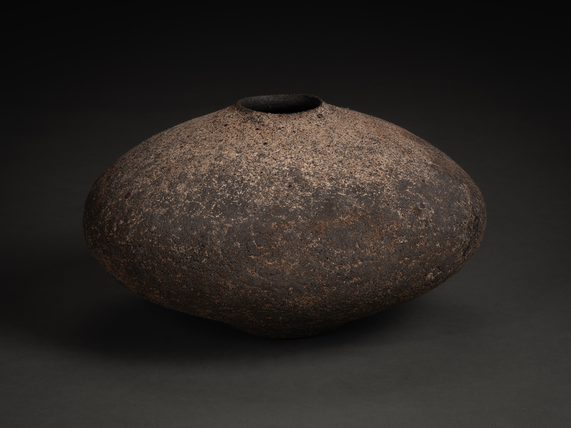 Vase by Jun Aoki, a low, wide ceramic vessel with a flattened, rounded form and narrow opening,...