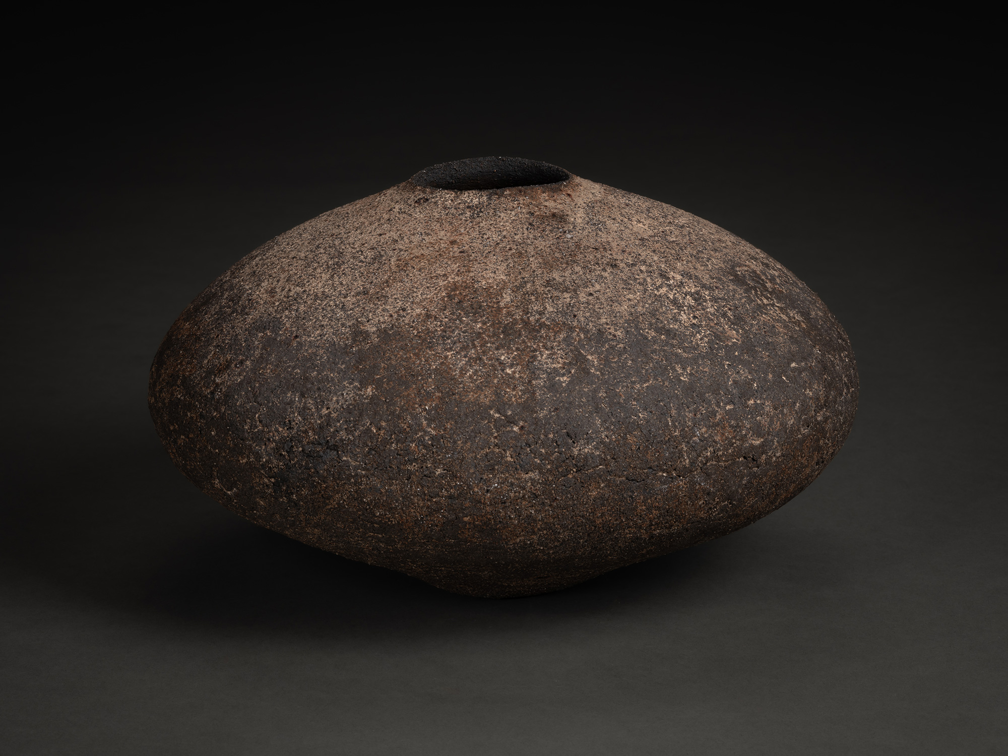 Vase by Jun Aoki, a low, wide ceramic vessel with a flattened, rounded form and narrow opening,...