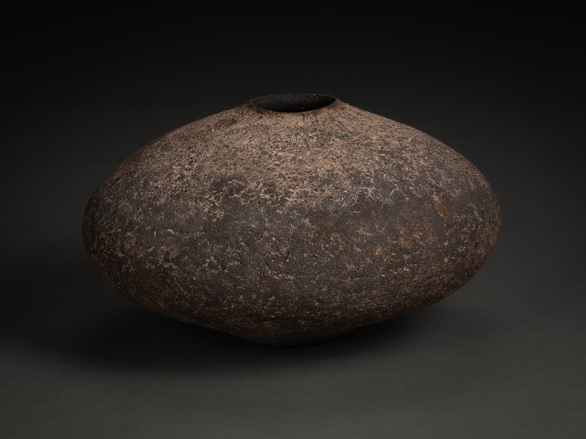 Vase by Jun Aoki, a low, wide ceramic vessel with a flattened, rounded form and narrow opening,...