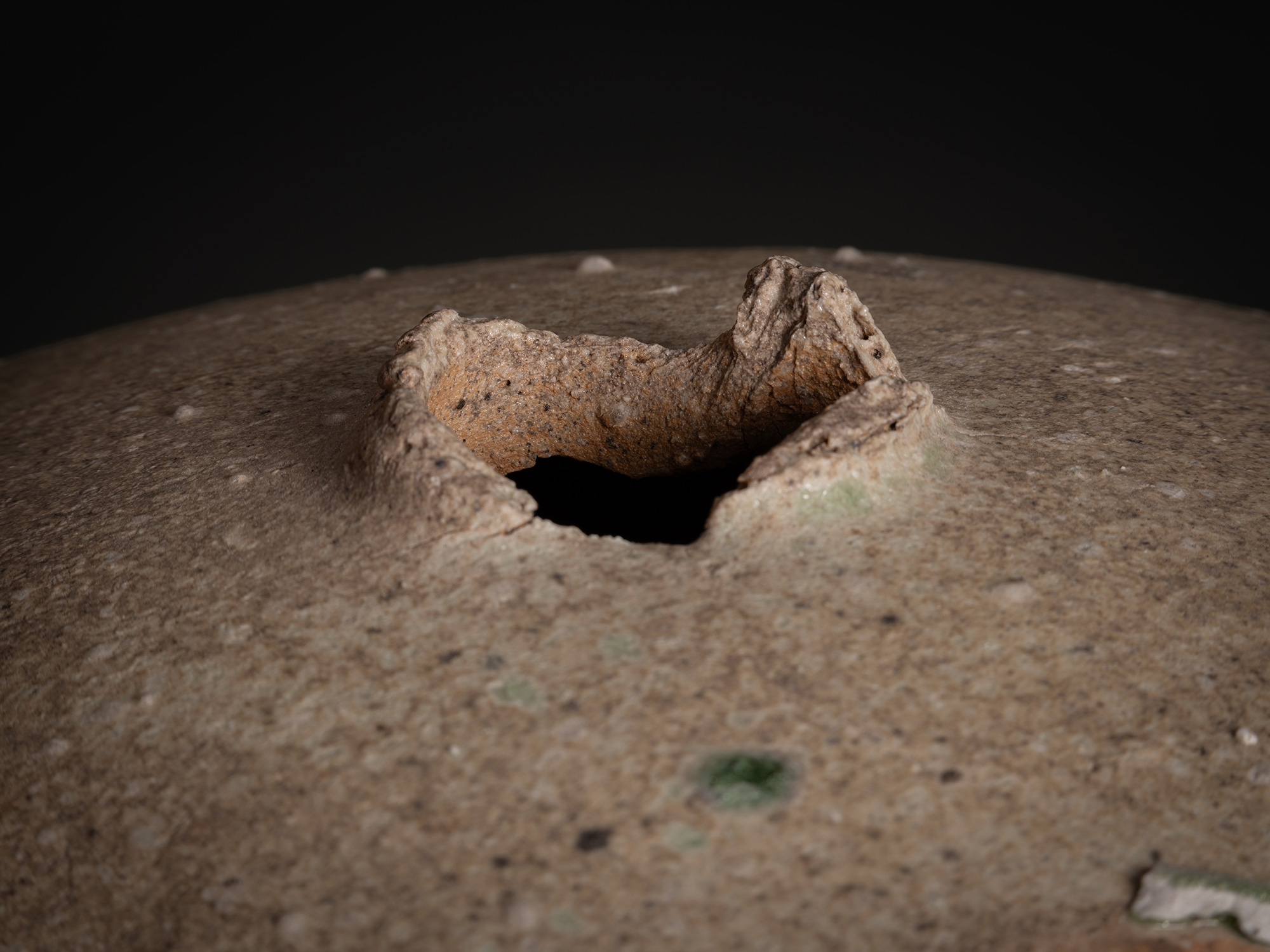Detail of Sphere by Tsujimura showing the top opening: a small, irregular aperture with a thick,...