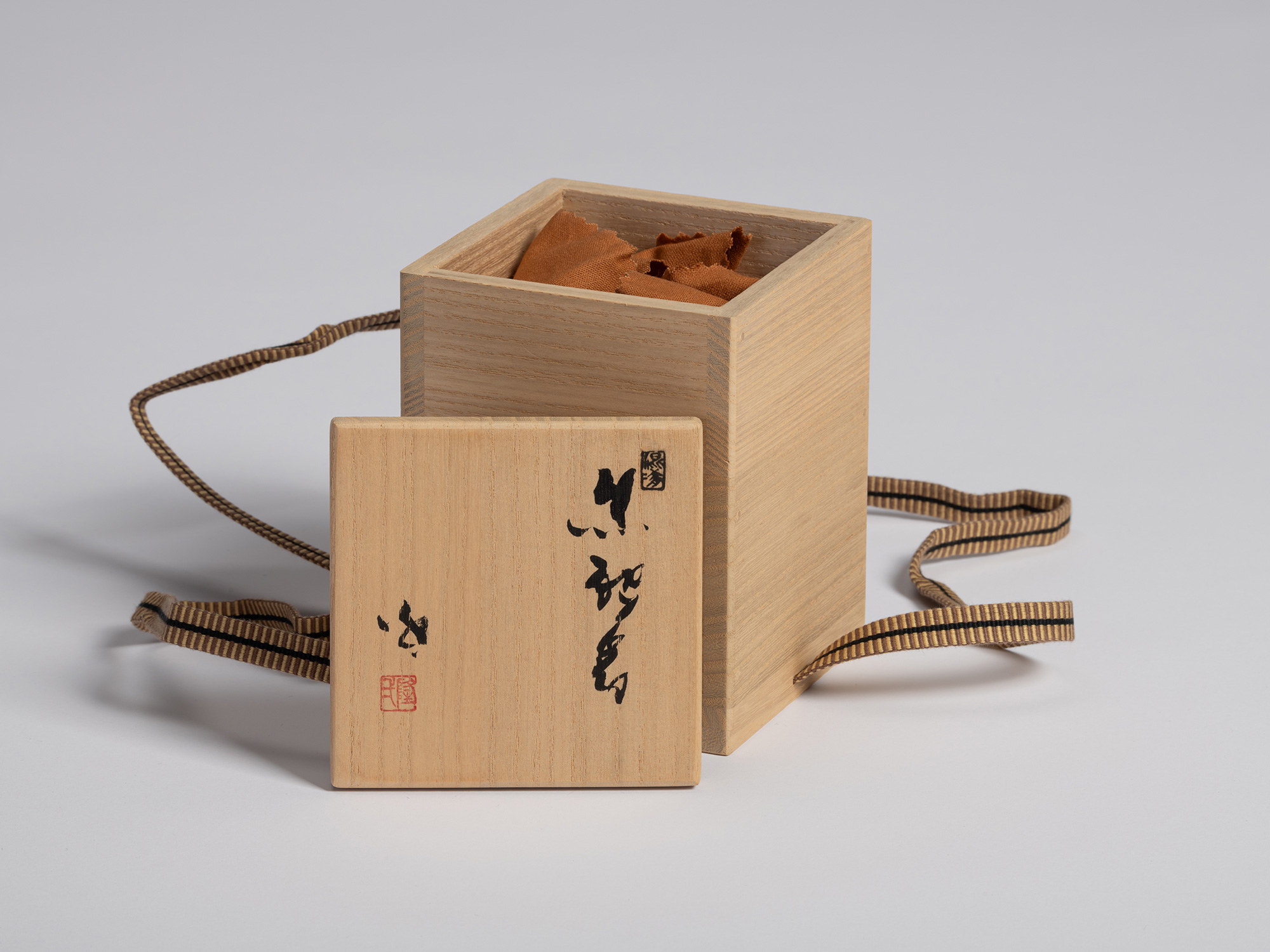 Tomobako storage box for a black guinomi by Ryuichi Kakurezaki with the wooden lid placed in front...