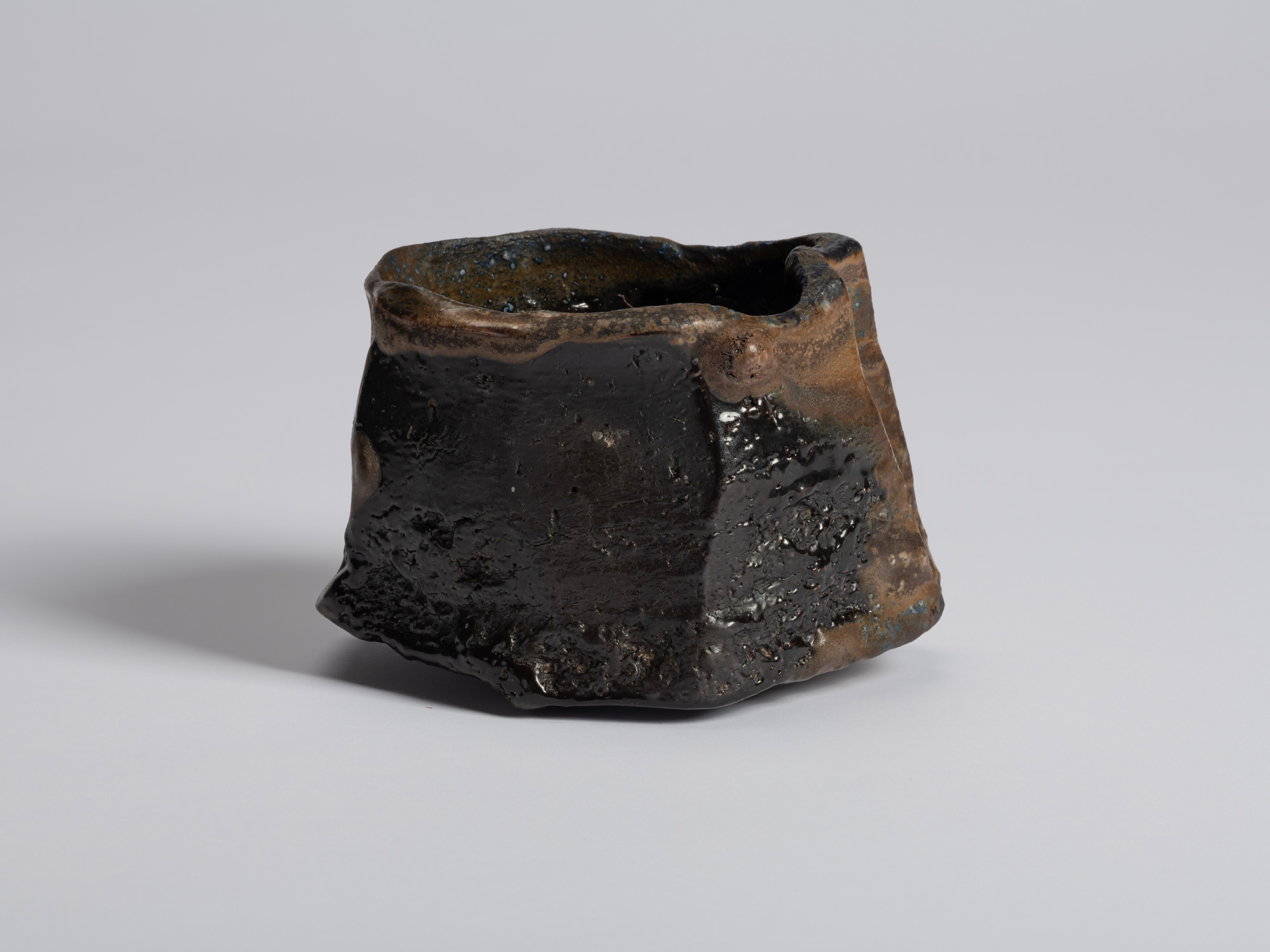 Black tea bowl by Ryuichi Kakurezaki with a rugged asymmetrical form and heavily textured black...