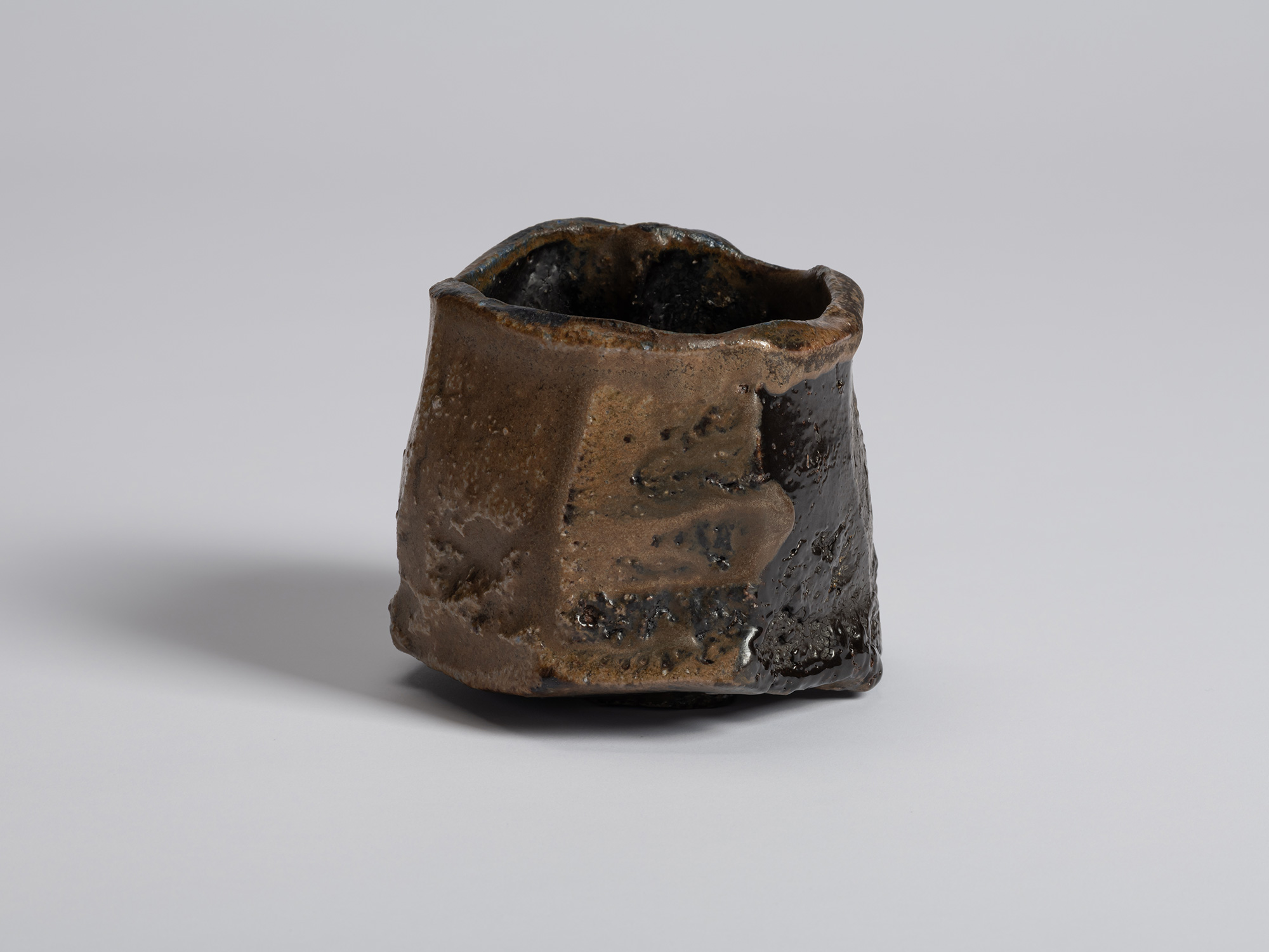 Black tea bowl by Ryuichi Kakurezaki shown from a frontal angle with alternating sections of brown...