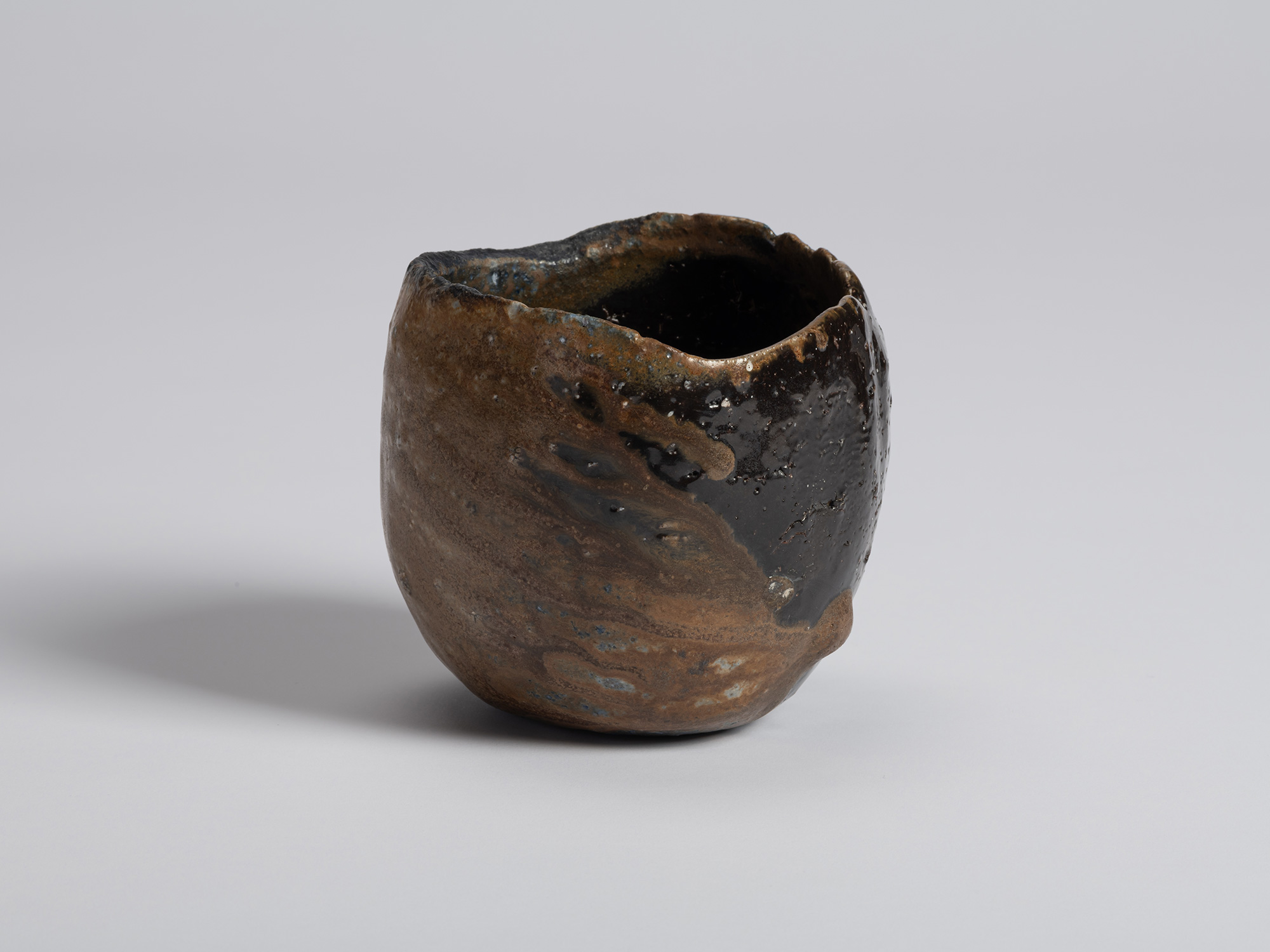 Black tea bowl by Ryuichi Kakurezaki with a rounded hand-formed body and uneven asymmetrical rim....