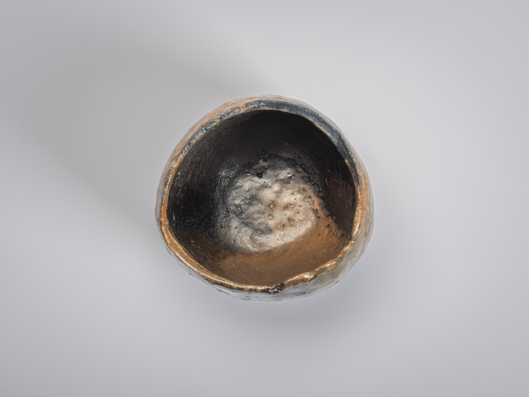 Aerial interior view of a black tea bowl by Ryuichi Kakurezaki showing a rounded asymmetrical interior...