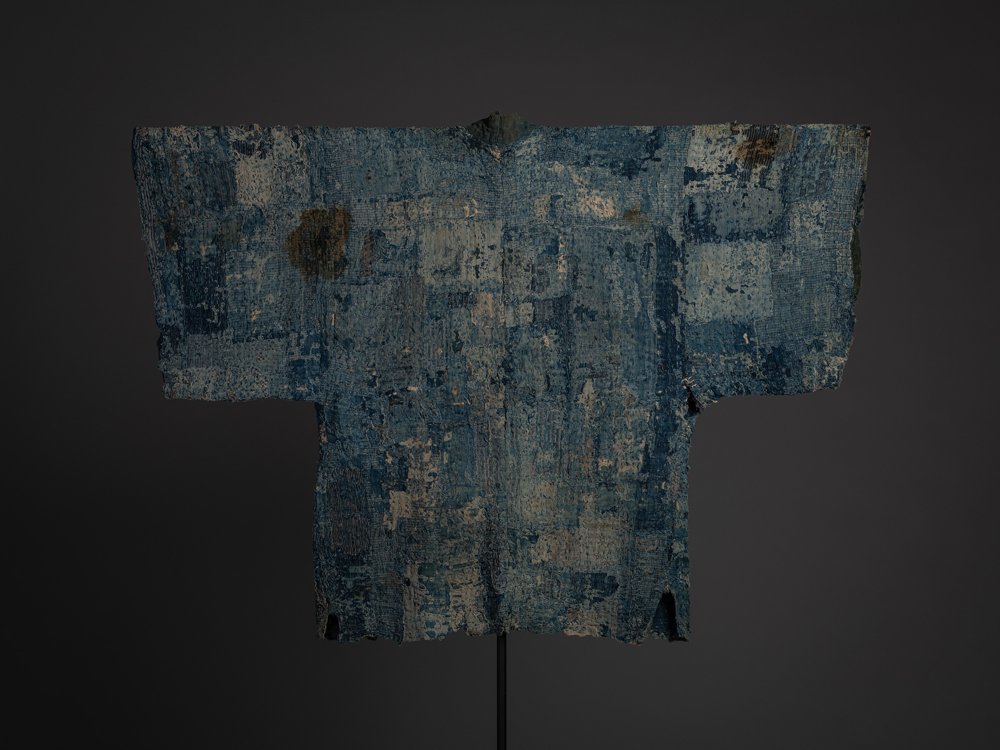 Alt text: Rear view of a Japanese boro hanten displayed on a black stand. The jacket features densely...