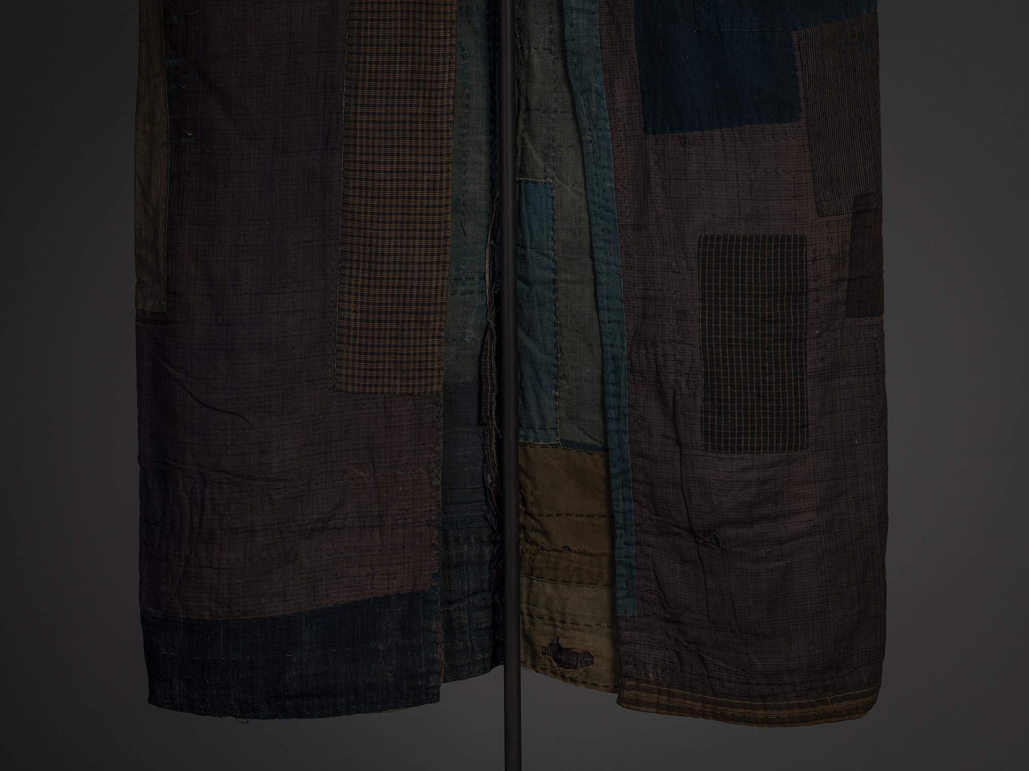 Detail of the lower front of a boro kimono featuring broad panels of faded purple-brown silk, indigo...
