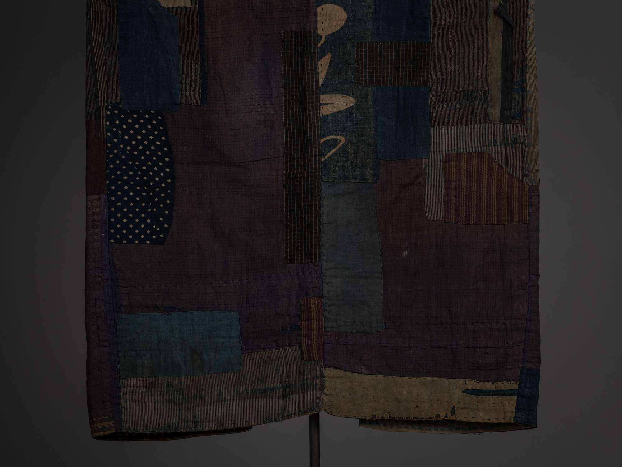 Detail of the lower back of a boro kimono featuring large purple-brown silk panels patched with...