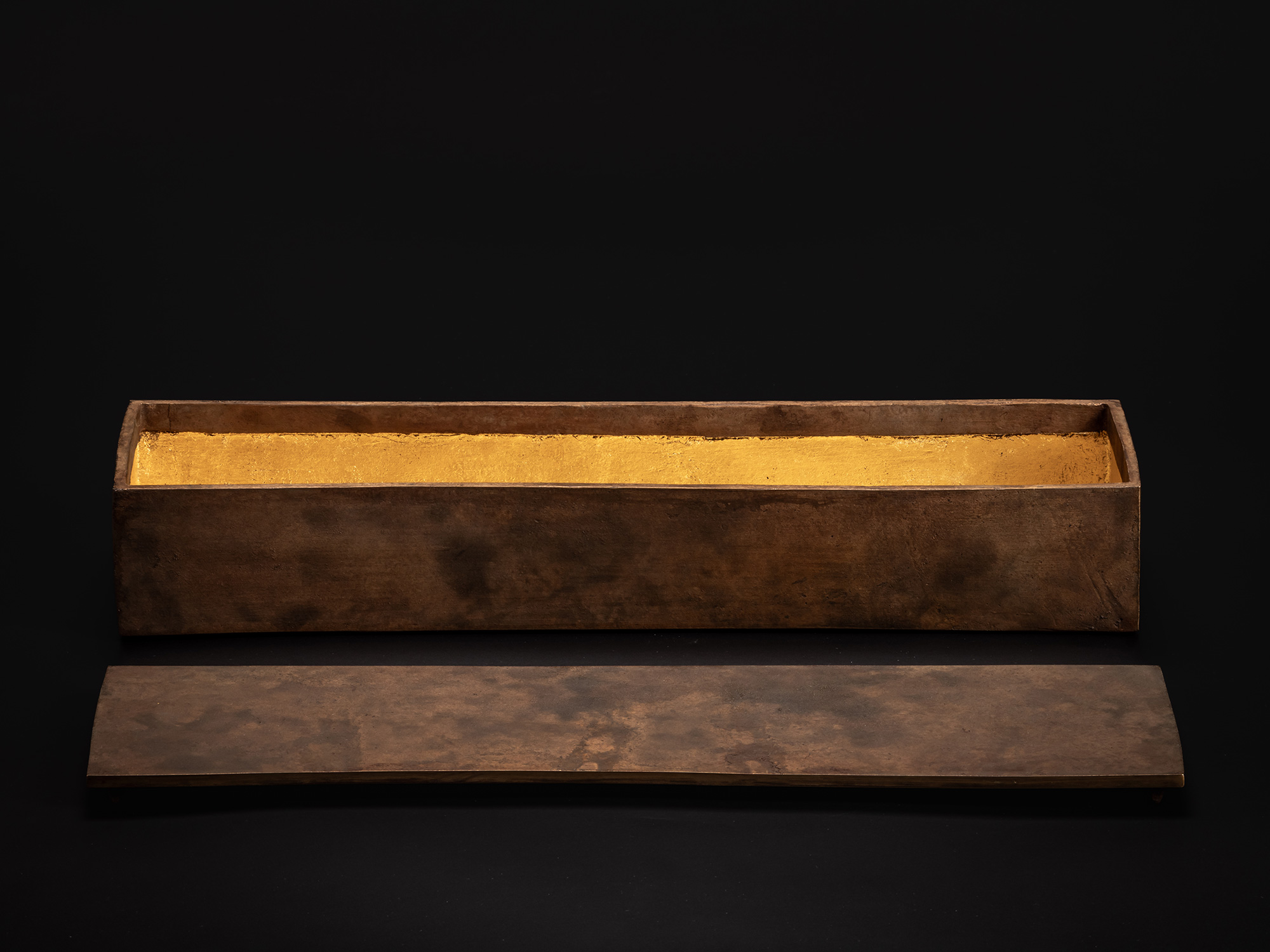Bronze box displayed with the lid removed and placed in front. The interior is lined with gold...
