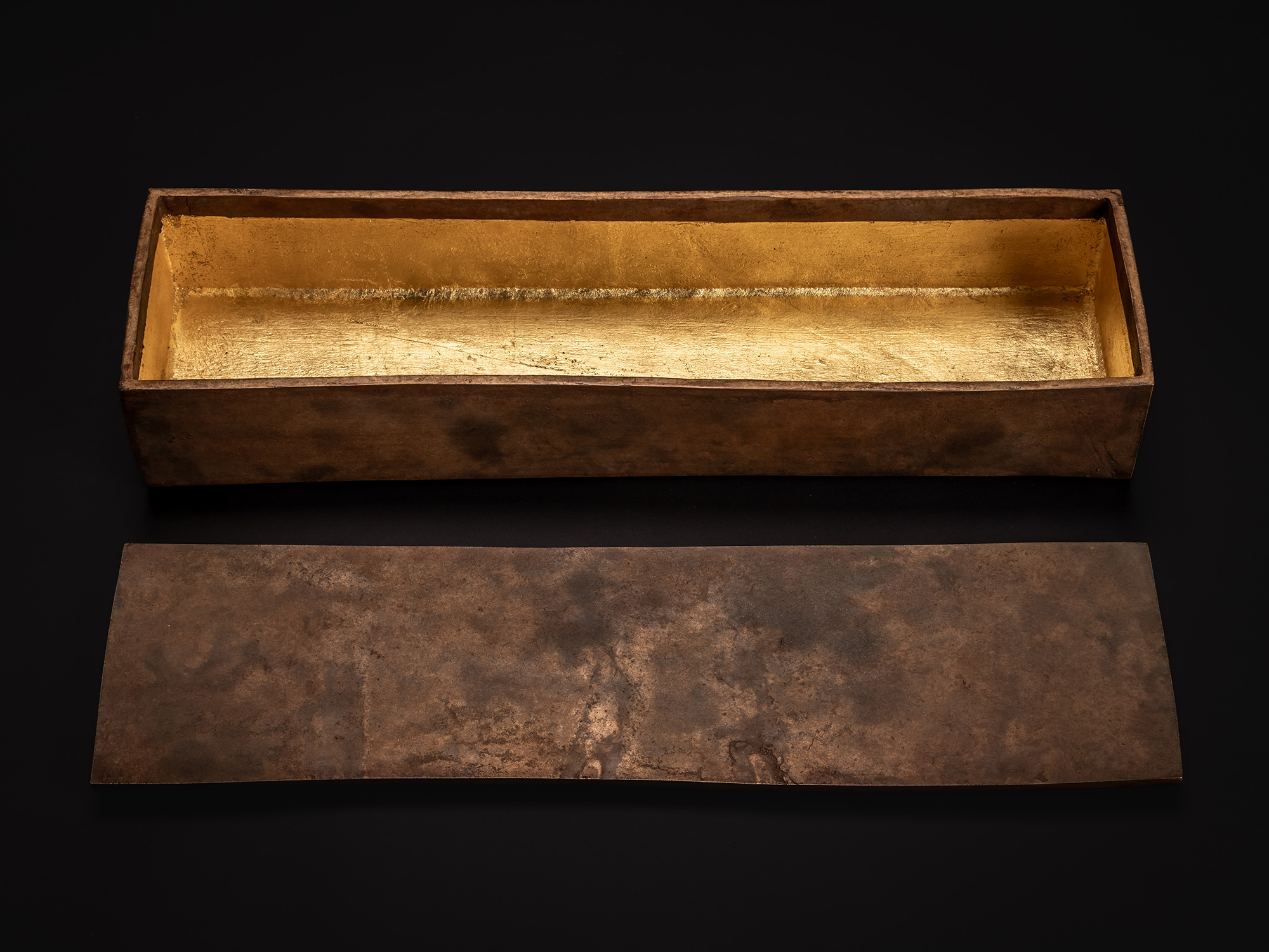 Angled view of Hatakeyama’s Bronze Box with the lid placed in the foreground. The gold-leaf-lined...