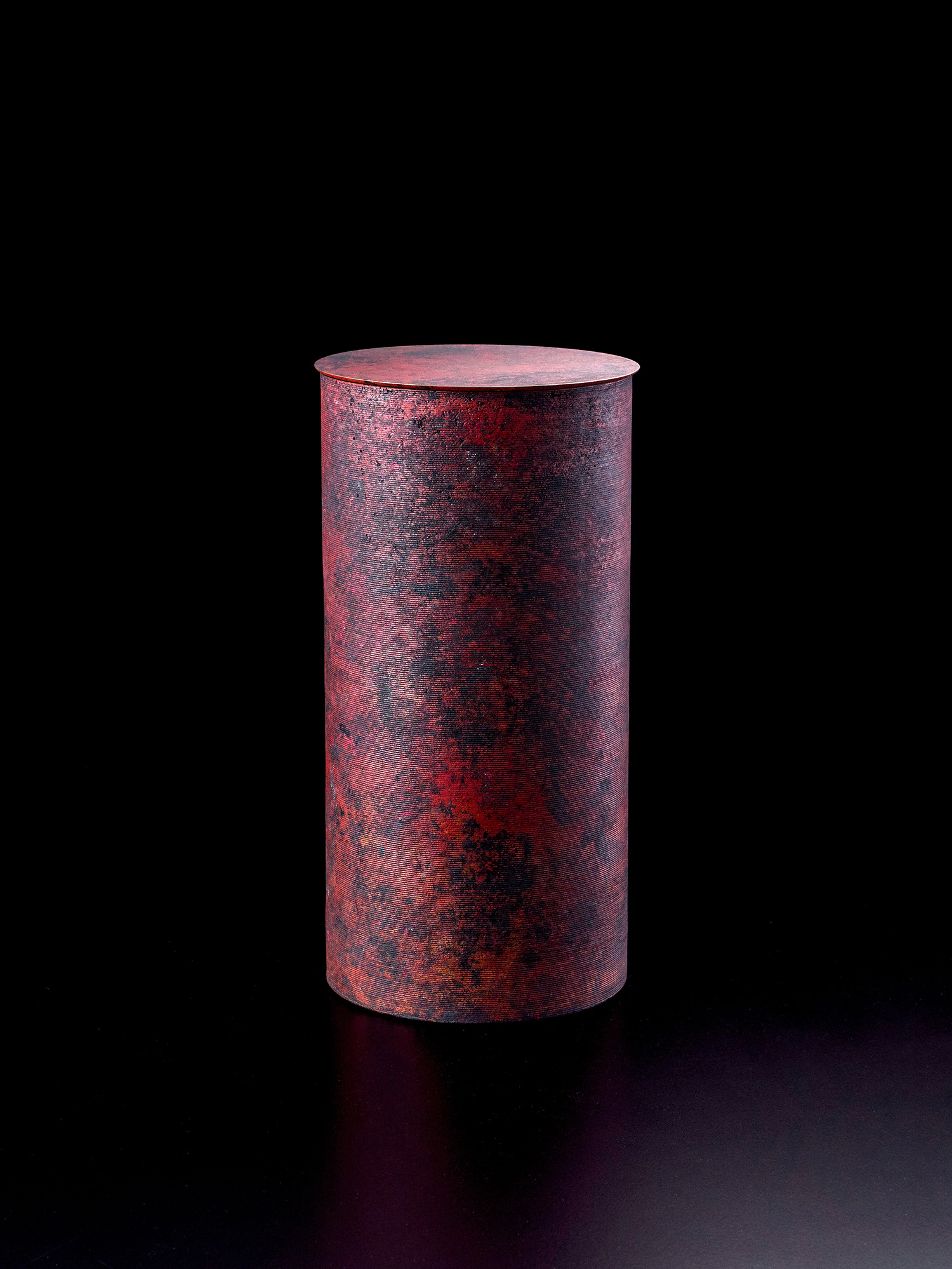 A tall, minimalist cylindrical bronze vessel with a flat, circular lid by Japanese metal artist...