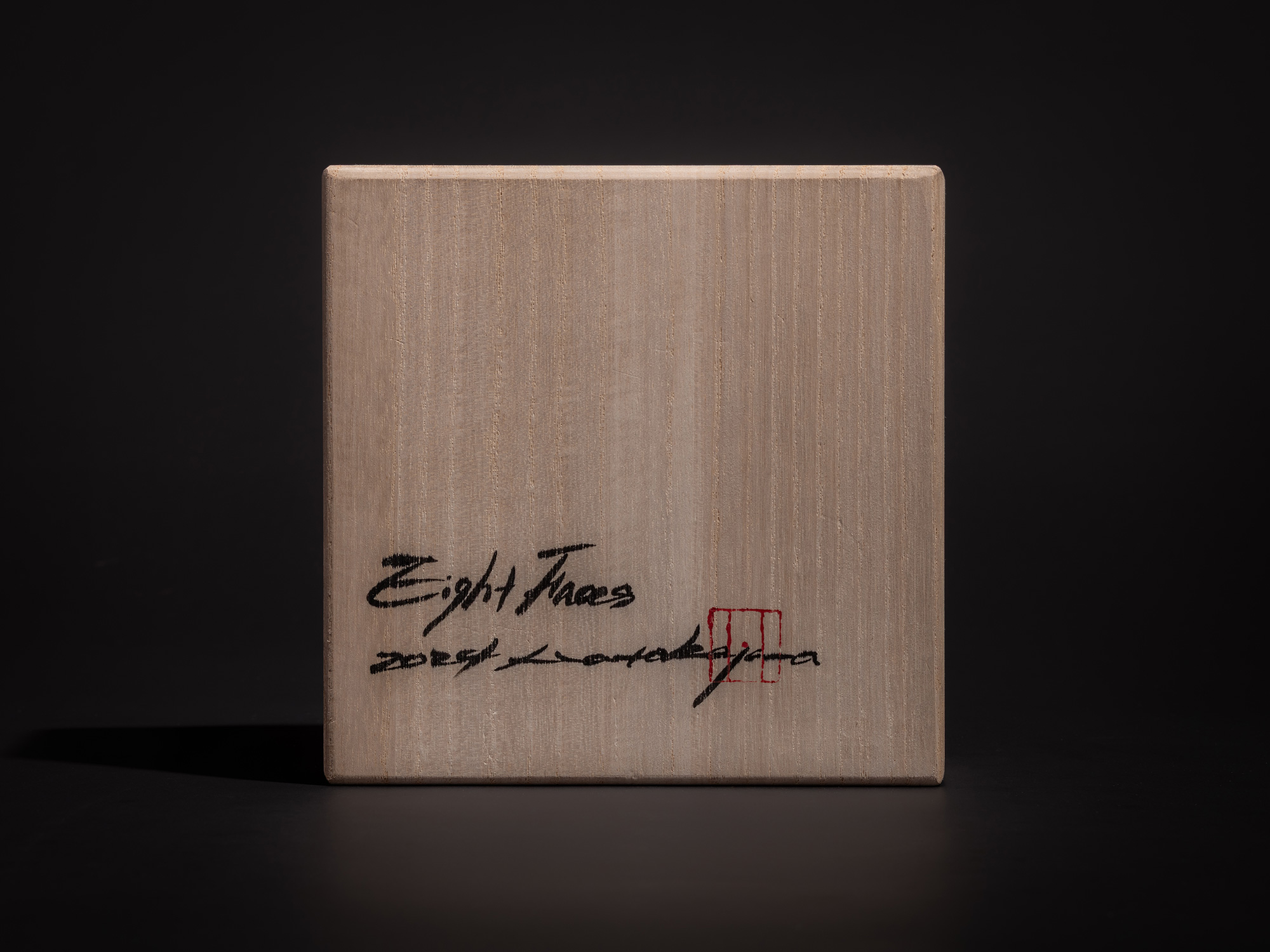 Lid of the tomobako for Eight Faces XVI by Koji Hatakeyama, showing a light wood surface with visible...