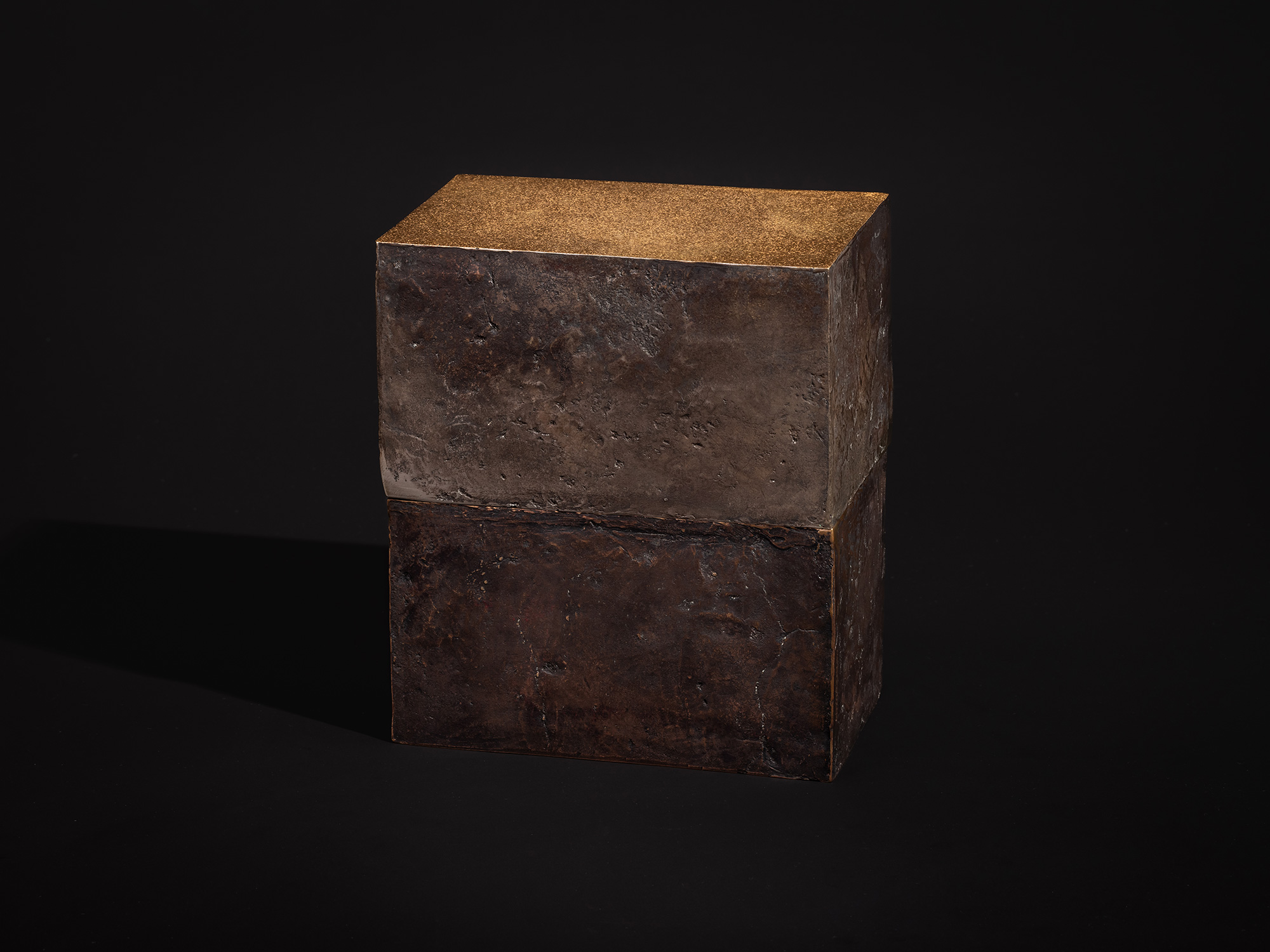 View of Inner Existence as a compact rectangular bronze box. The sculpture features heavily textured...
