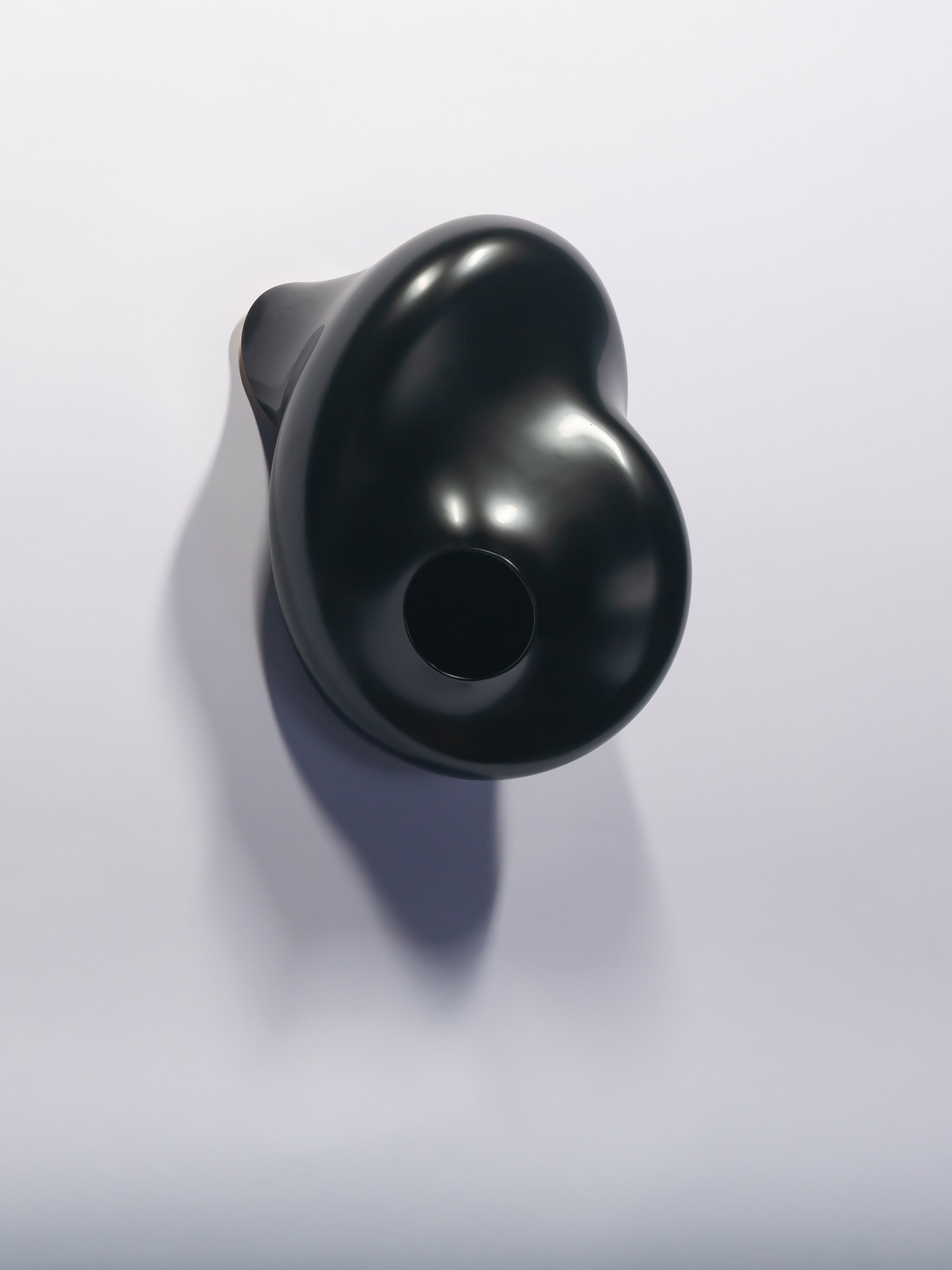 A wall-mounted, glossy black urushi lacquer sculpture titled Membrane Spot by Genta Ishizuka, viewed...