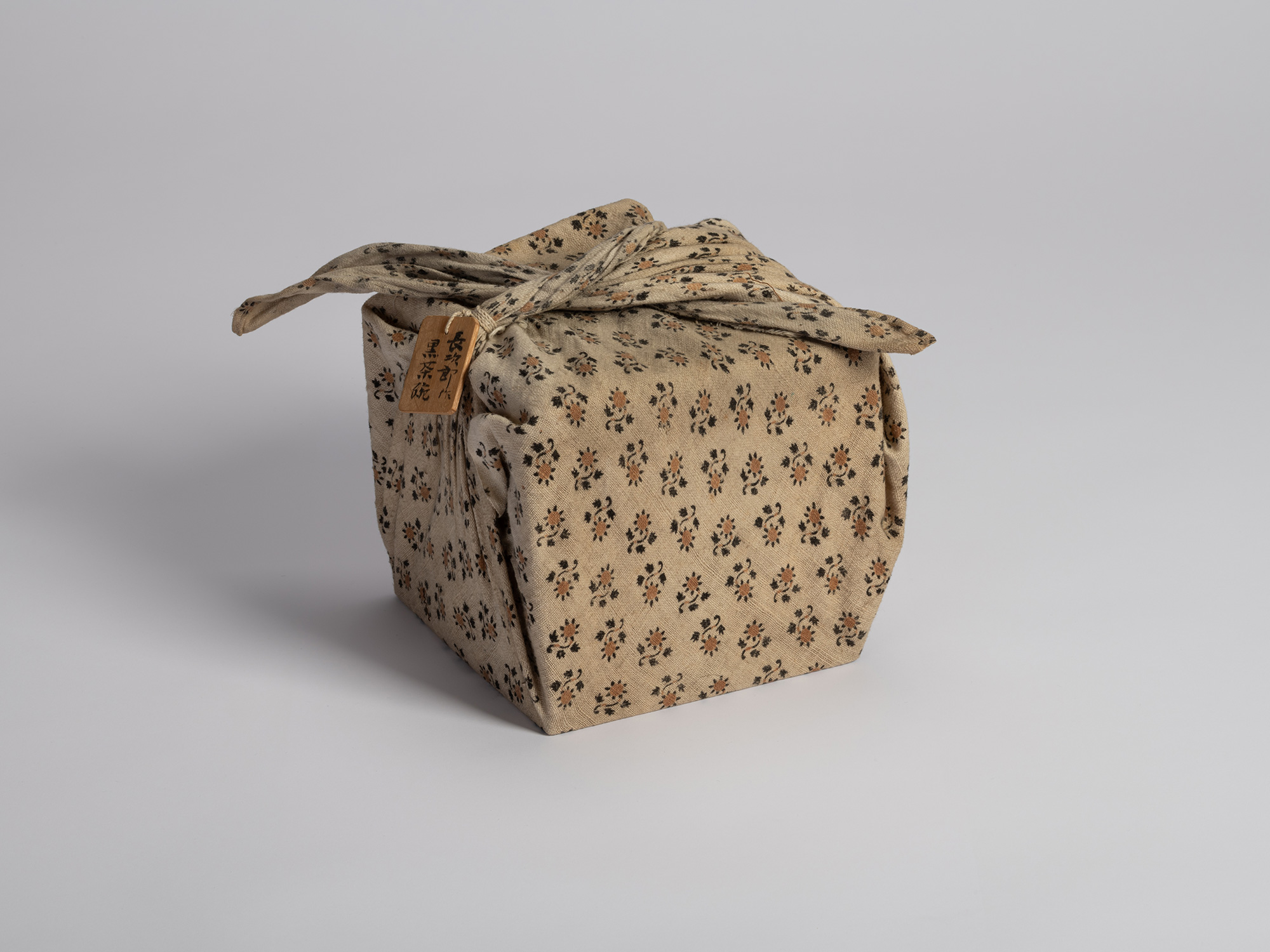 Photograph of a traditional Japanese wooden storage box (tomobako) wrapped in a protective, neutral...