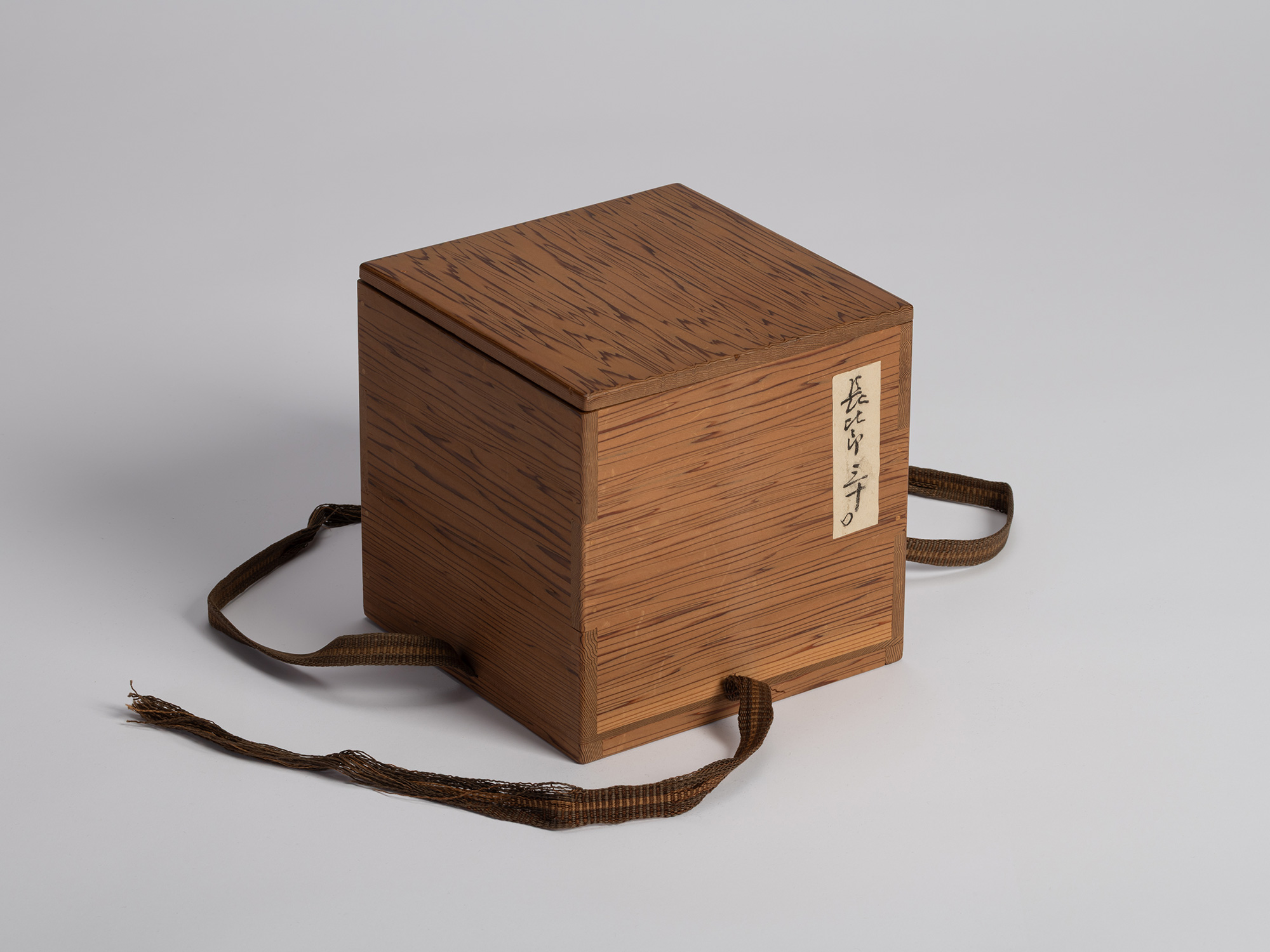A square paulownia wooden storage box (tomobako) used for housing a historic Raku tea bowl attributed...