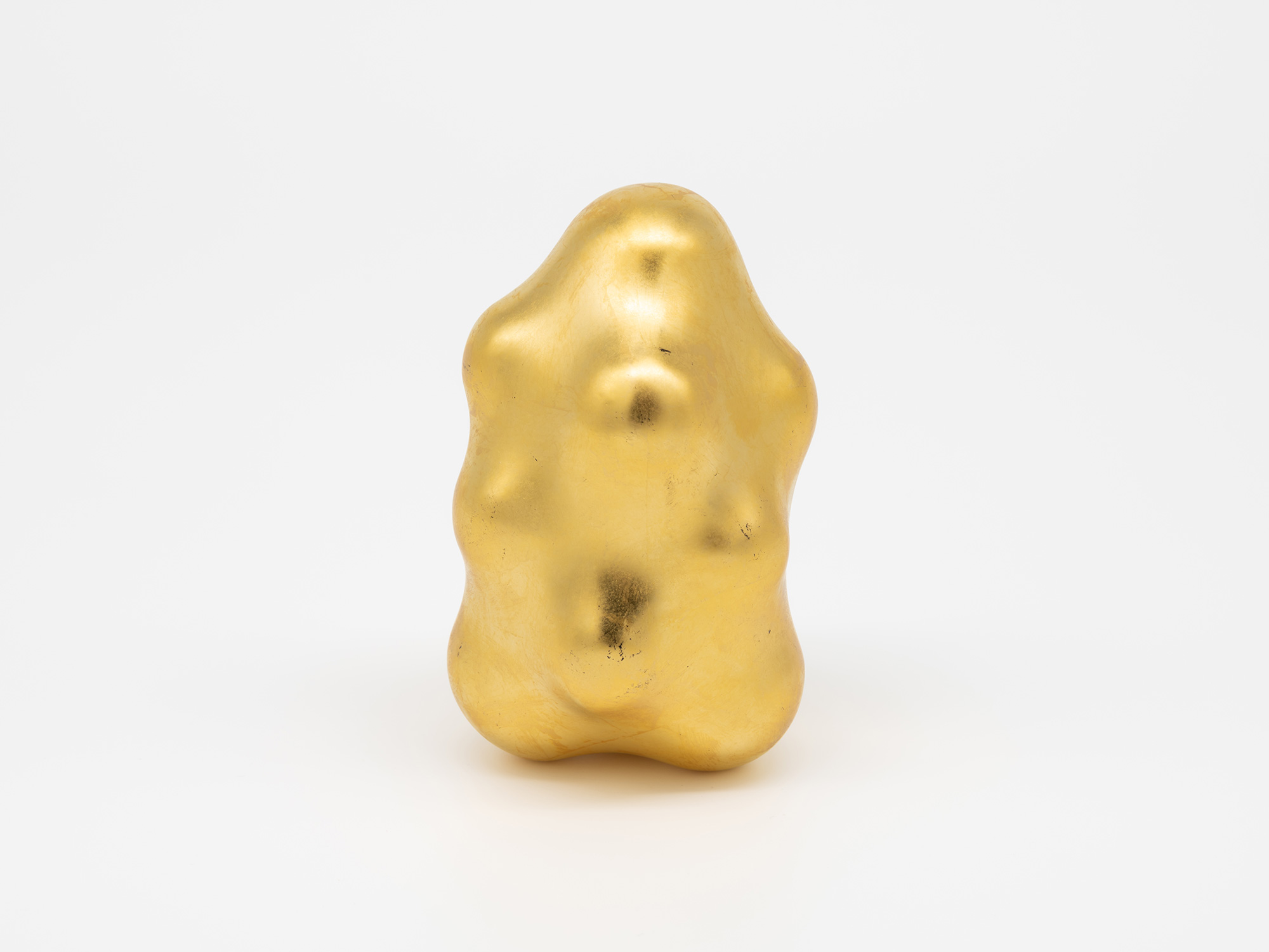 View of Genta Ishizuka's Untitled gold sculpture against a seamless white background. The biomorphic...