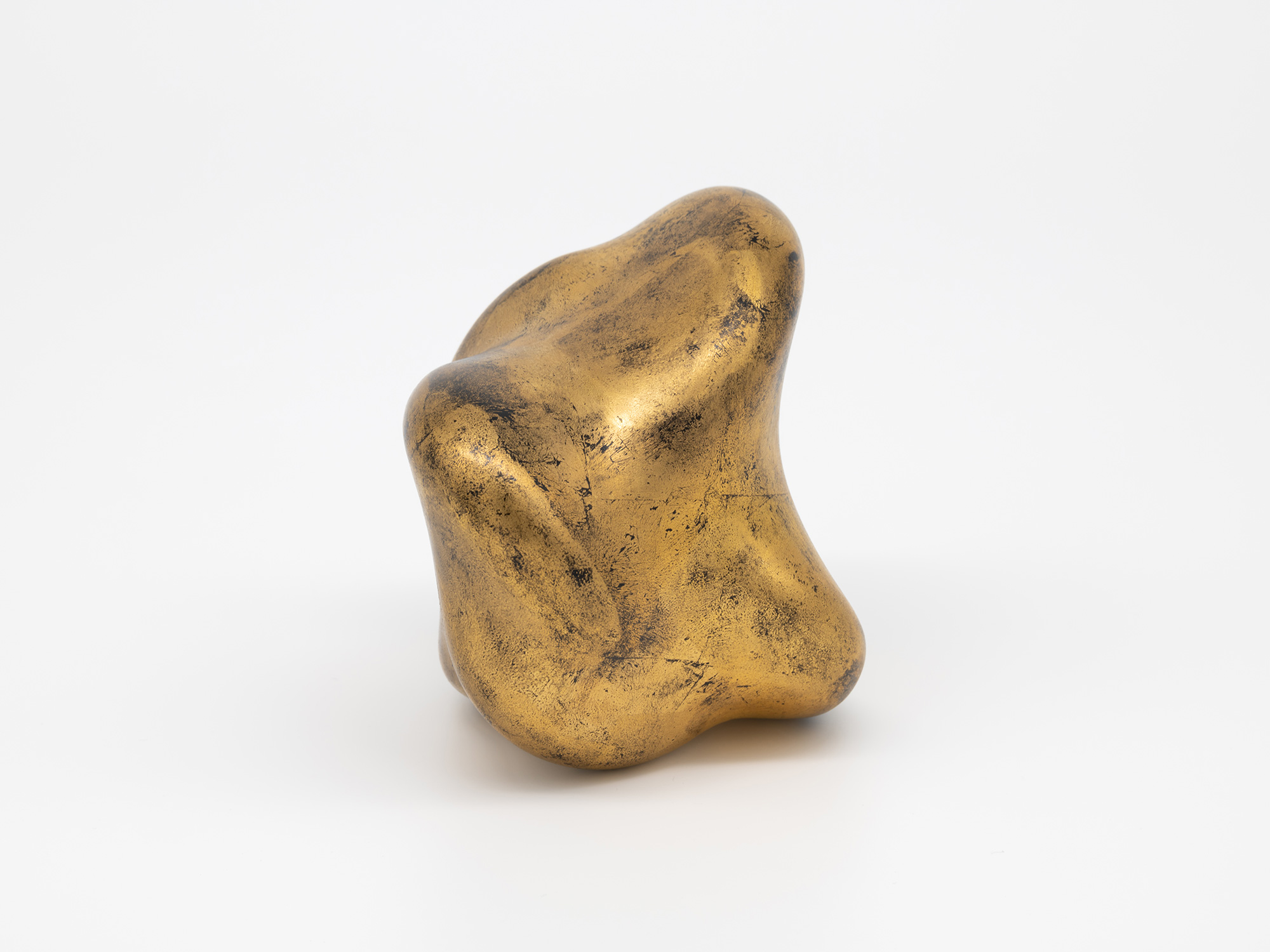 A side view of Genta Ishizuka's sculpture Untitled (faded-gold) against a seamless white background,...