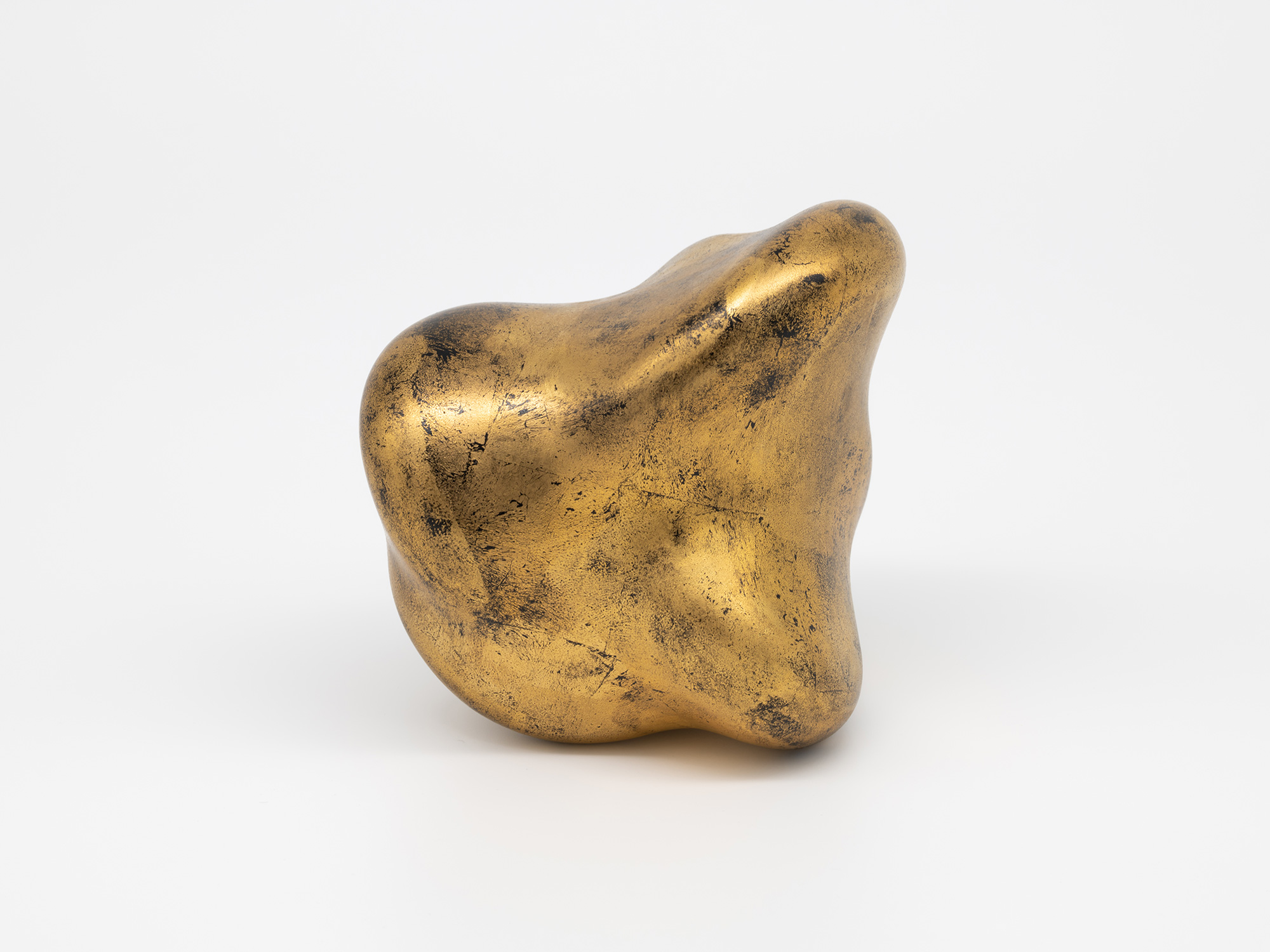 A side view of Genta Ishizuka's sculpture Untitled (faded-gold) against a seamless white background,...