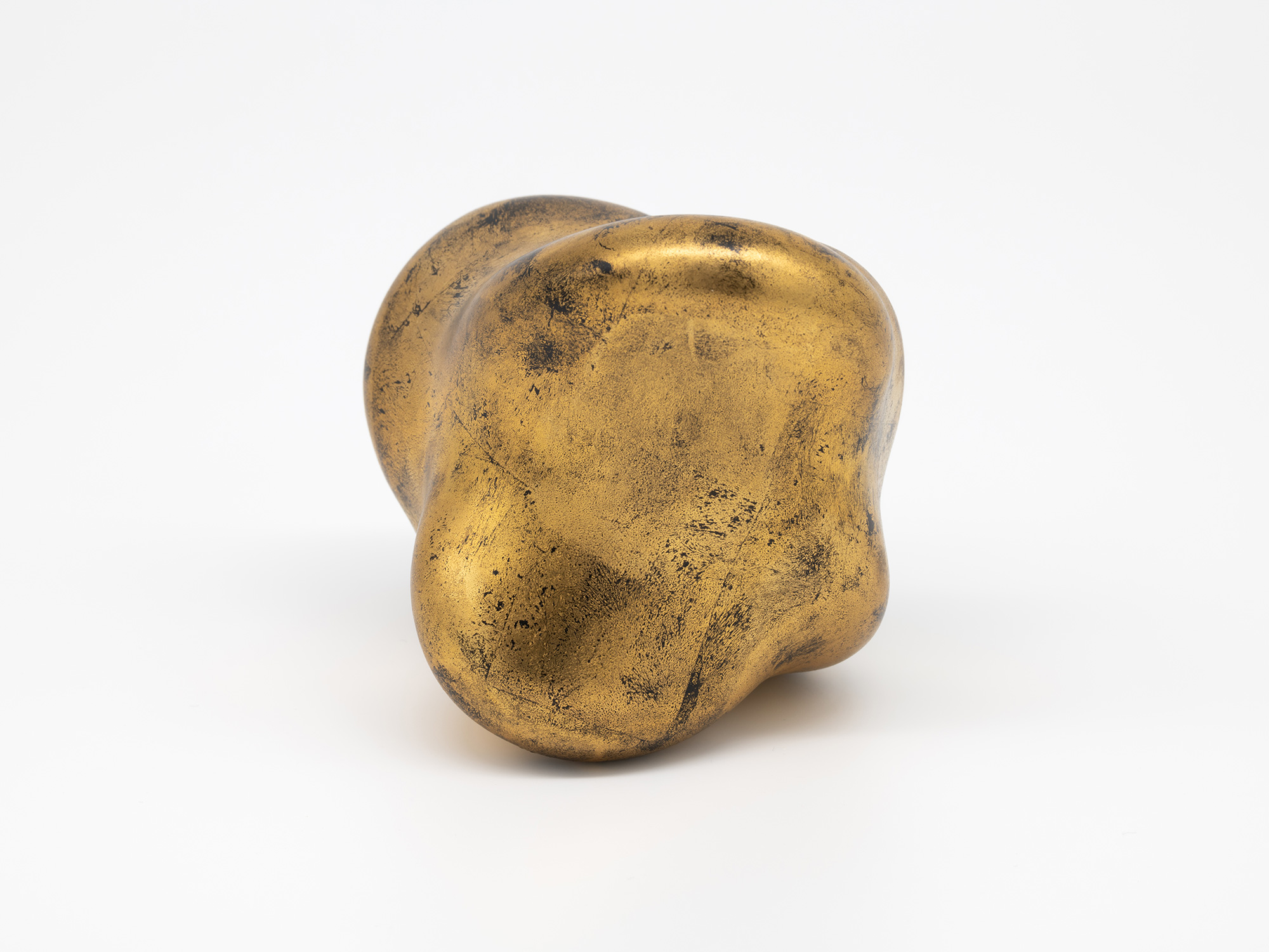 A side view of Genta Ishizuka's sculpture Untitled (faded-gold) against a seamless white background,...