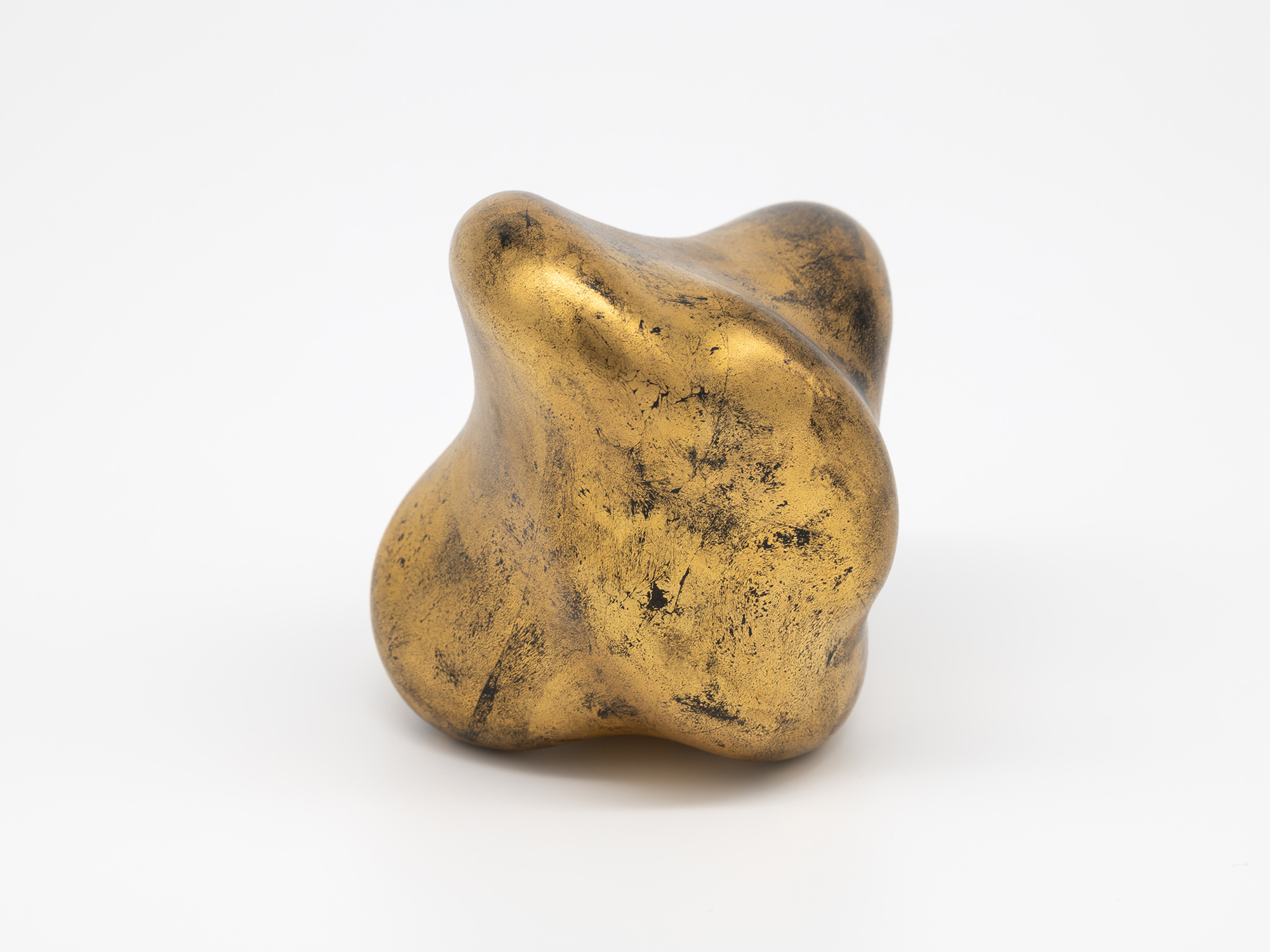 A side view of Genta Ishizuka's sculpture Untitled (faded-gold) against a seamless white background,...