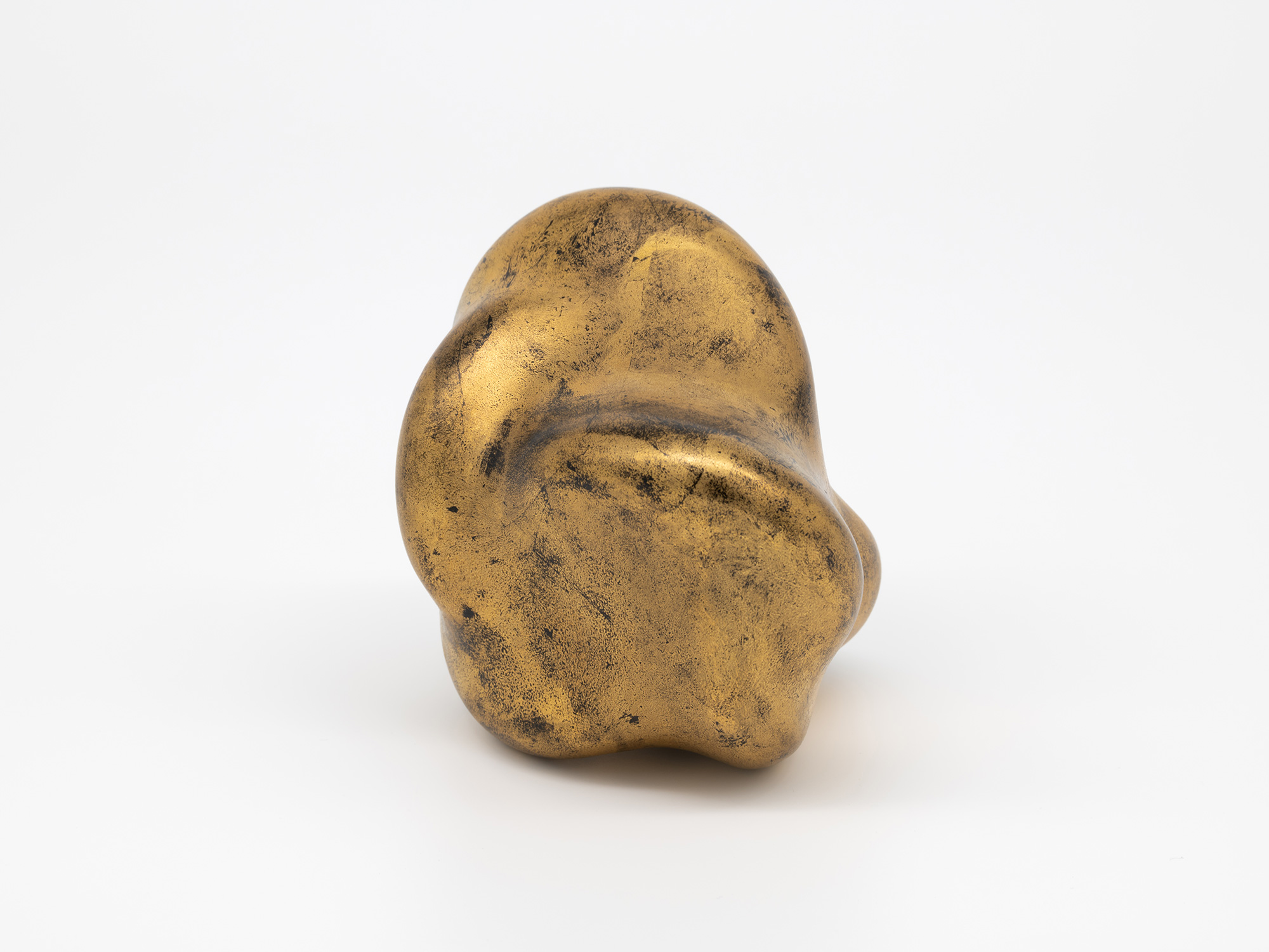 A side view of Genta Ishizuka's sculpture Untitled (faded-gold) against a seamless white background,...