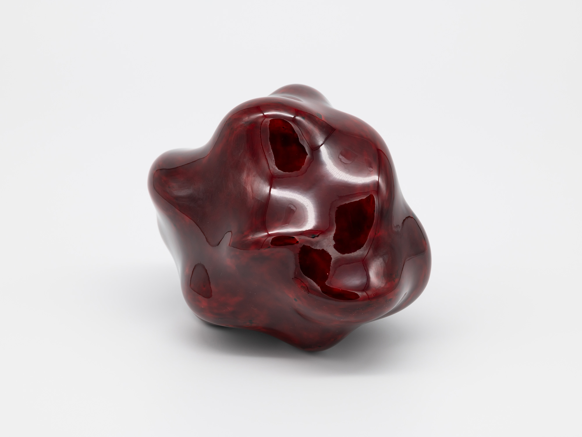 A small, freestanding contemporary sculpture composed of smooth, glossy lacquer. The biomorphic...