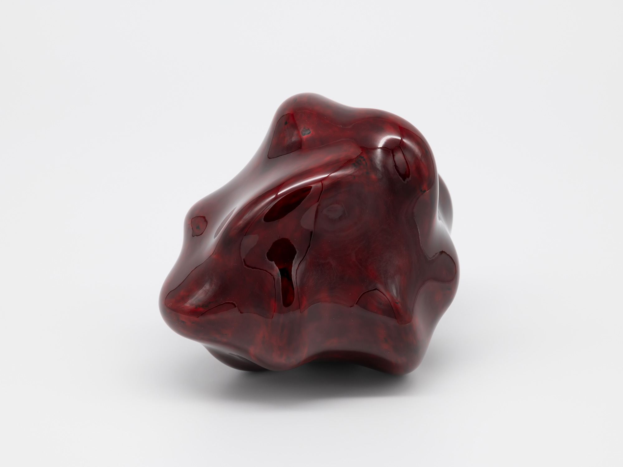 A small, freestanding contemporary sculpture composed of smooth, glossy lacquer. The biomorphic...