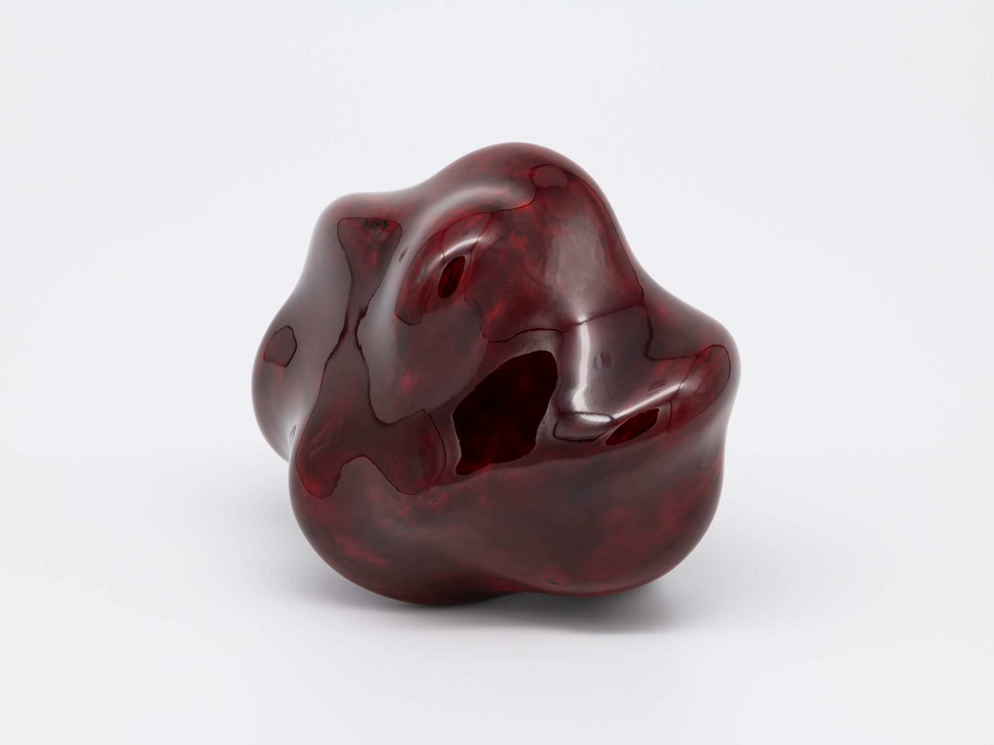 A small, freestanding contemporary sculpture composed of smooth, glossy lacquer. The biomorphic...