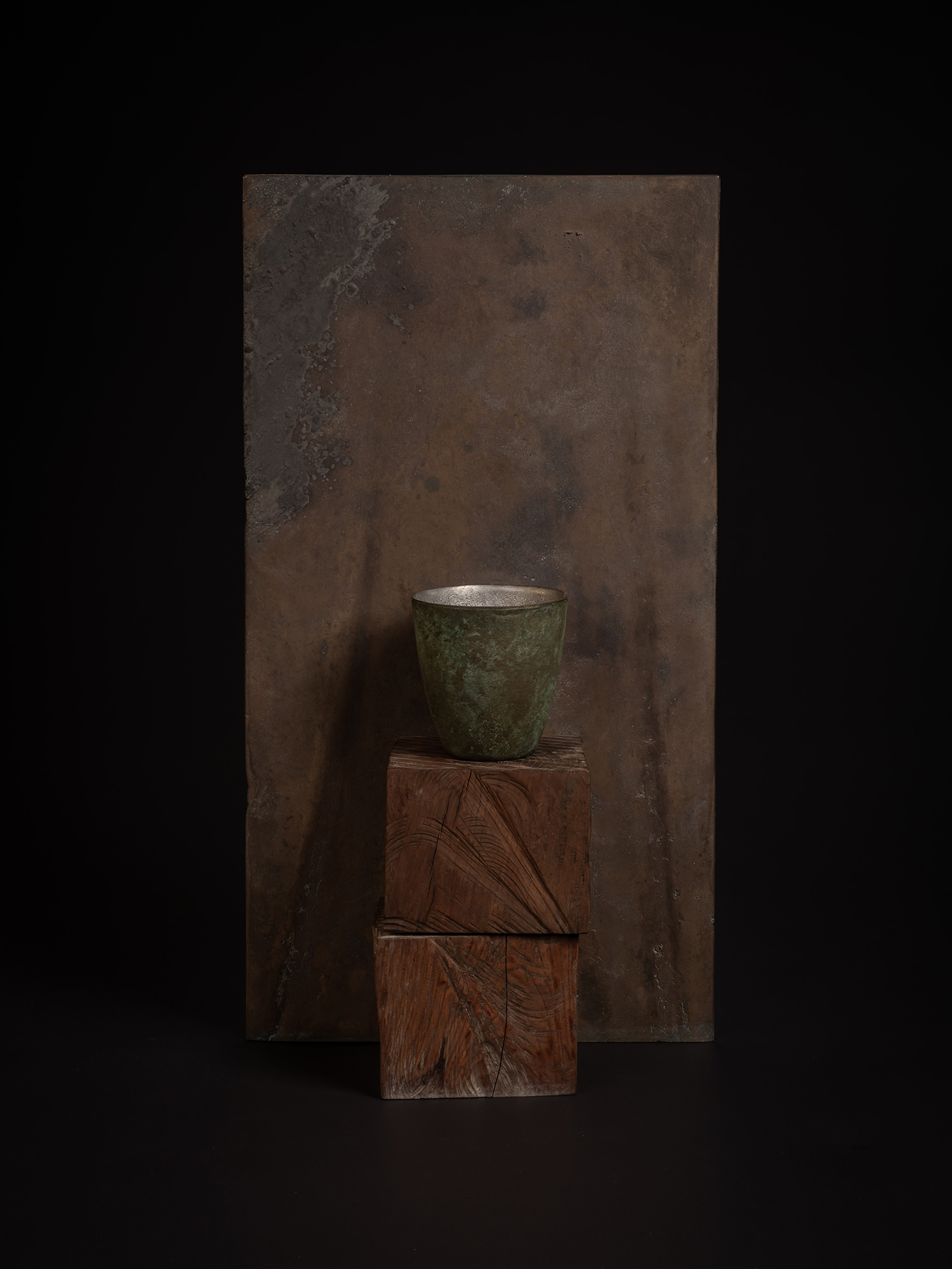 A narrow bronze artwork by Koji Hatakeyama featuring a tall rectangular bronze panel with mottled...