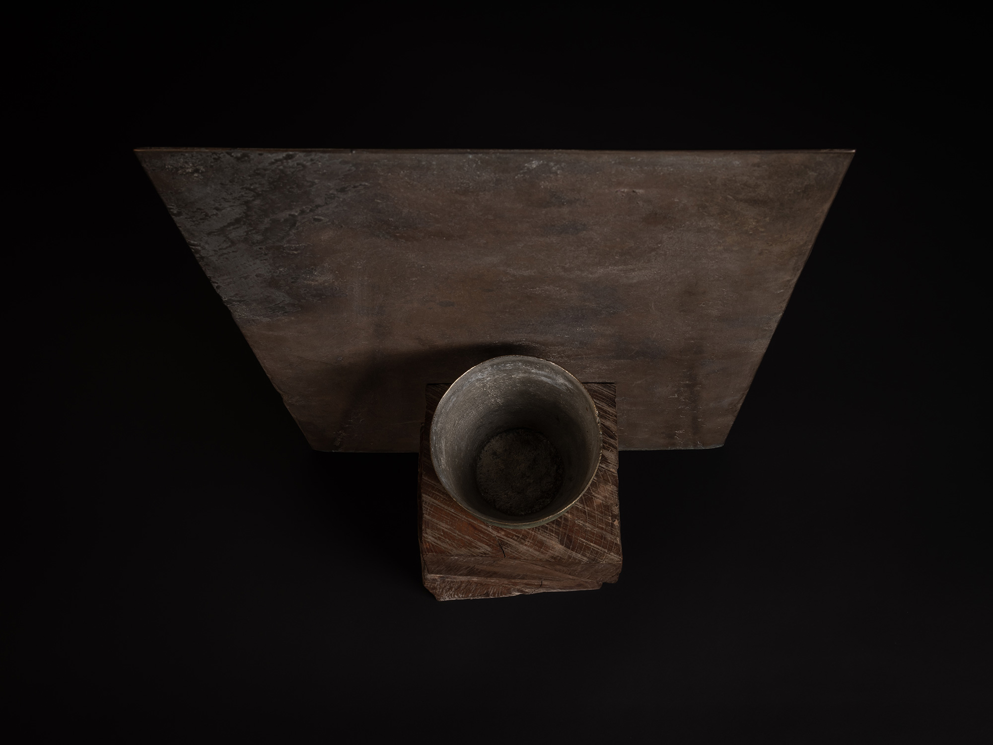 Aerial view of a bronze artwork by Koji Hatakeyama featuring a narrow green-patinated vessel resting...