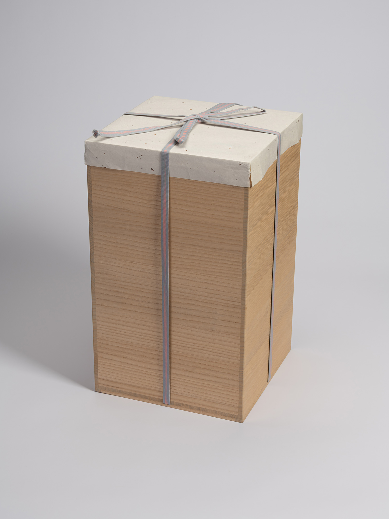 A tall, rectangular paulownia wooden storage box (tomobako) crafted to hold a contemporary ceramic...