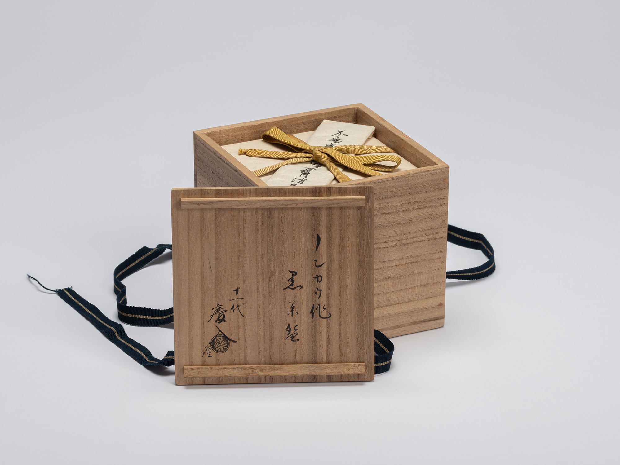 The square, medium-toned paulownia wood middle storage box—the second of three layers—sits open...