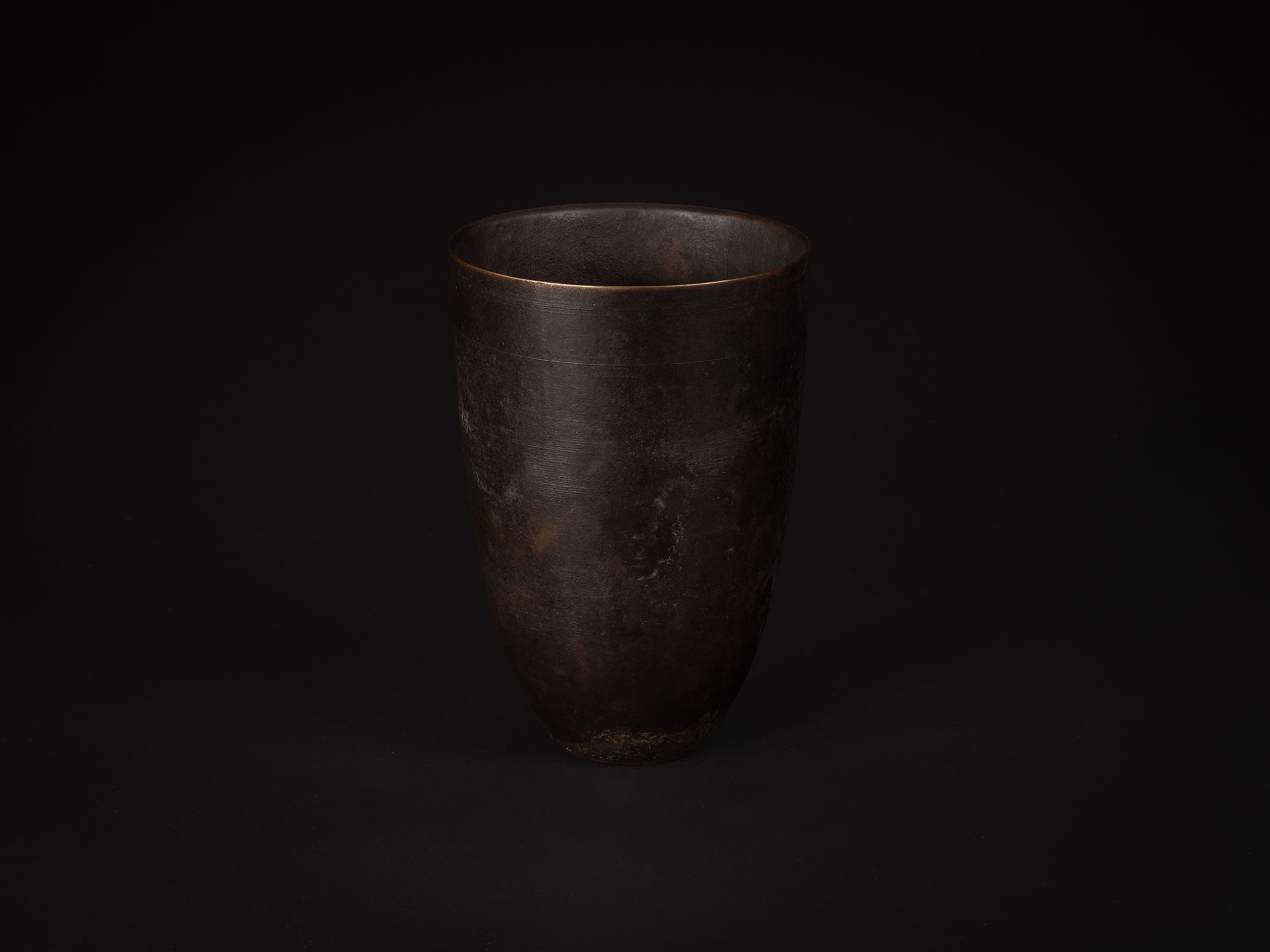bronze as Bronze No. 9 is a vessel with gently tapering sides and a rounded base. The bronze surface...