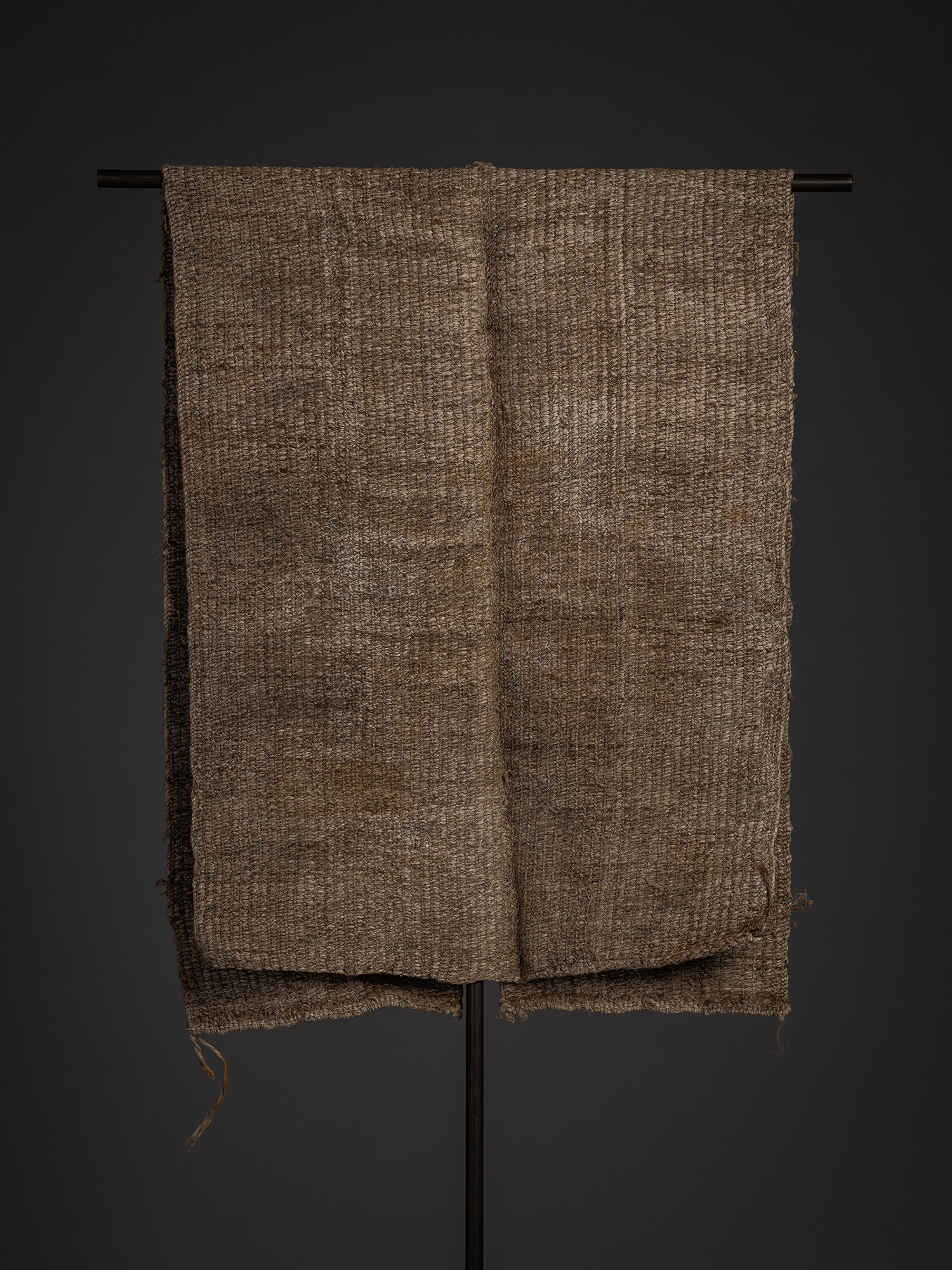 Rear view of the angin sodenashi displayed on a black stand. The sleeveless garment hangs open...