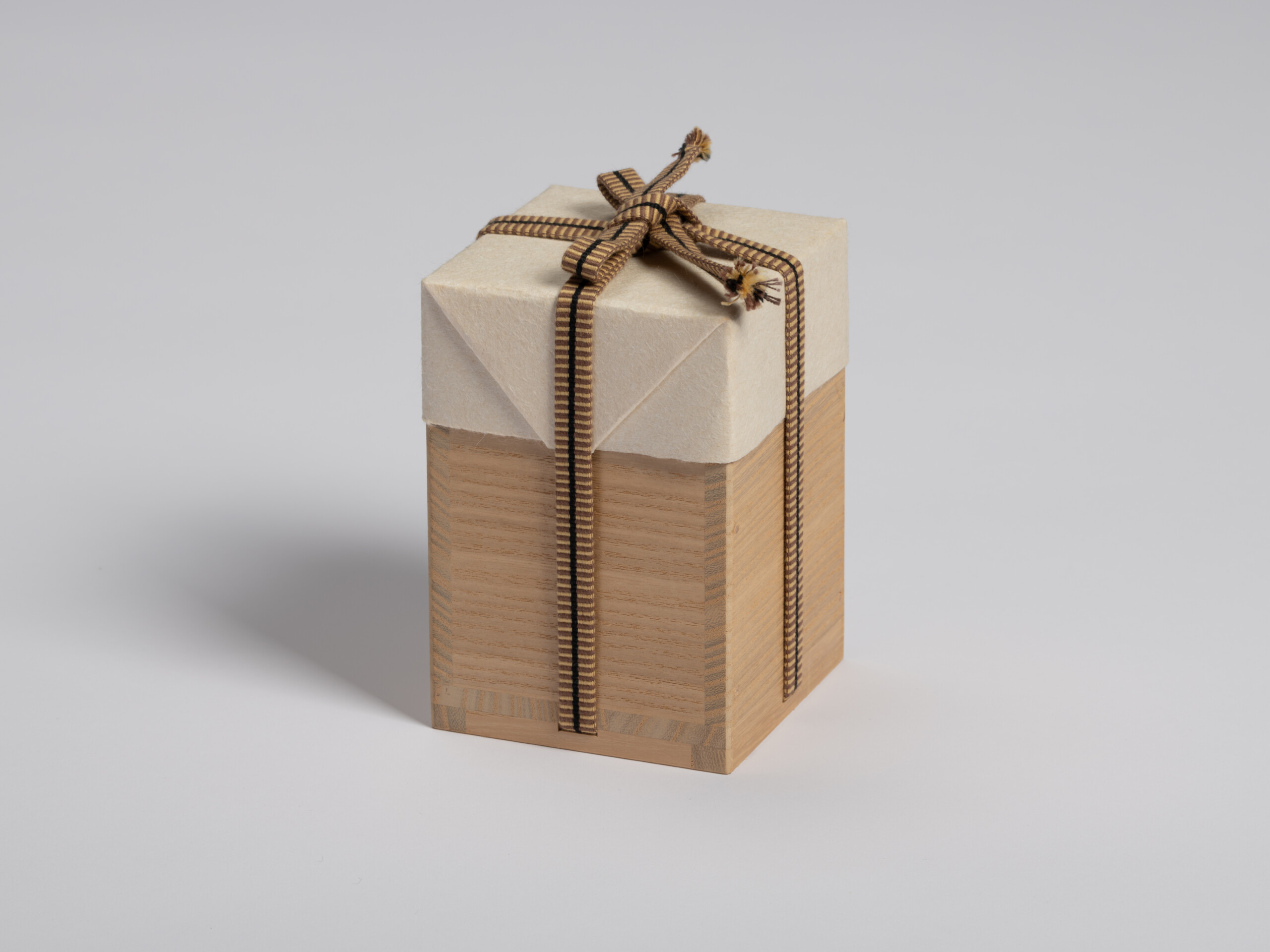 Paulownia wood tomobako wrapped in protective white paper and secured with a brown-and-black striped...