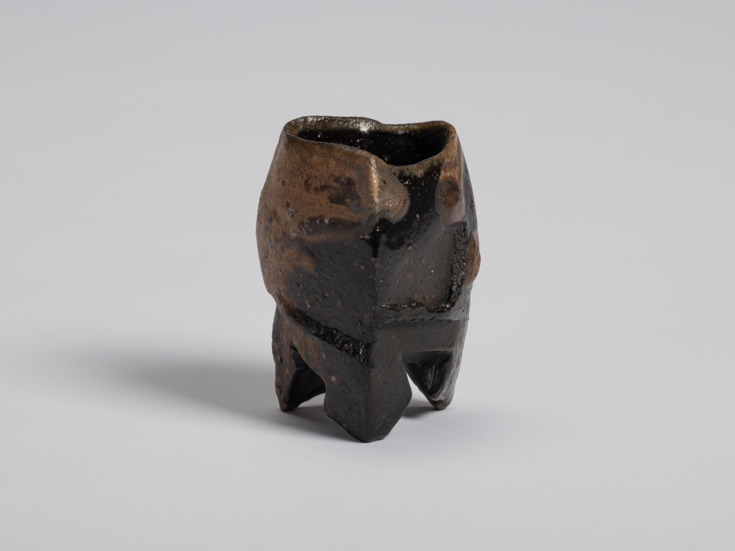 View of Black Guinomi showing a glossy black glaze flowing across the front and into warm brown...