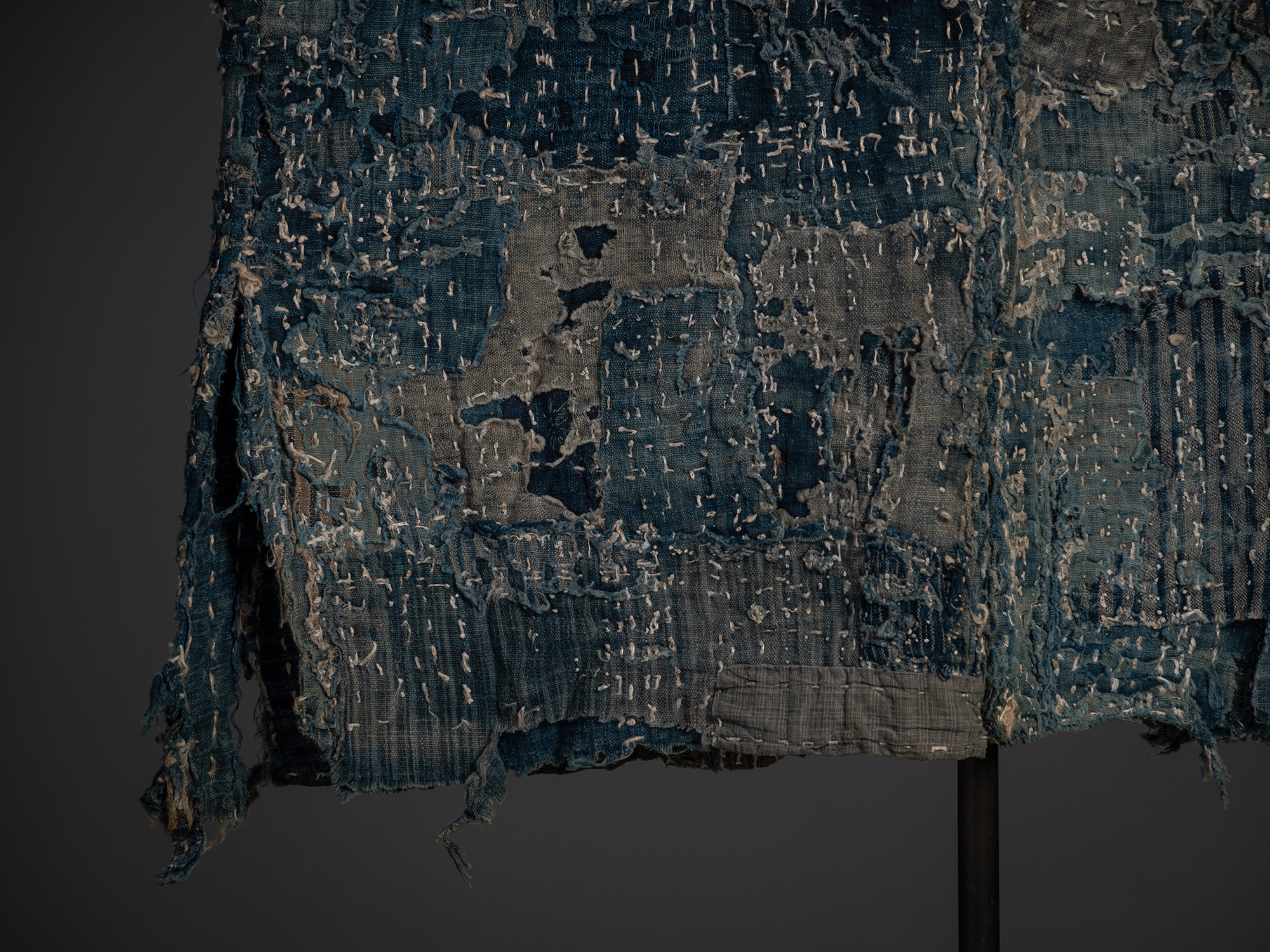 Detail of the lower back section of the coat. Numerous patched textiles of differing weaves and...